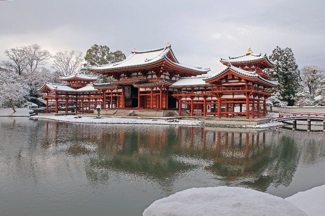 正月早々、雪が降った。それも元日京都。<br />気が付いたのは、夕方３時。もう暗くなる。いけない。残念<br />結構降っていたので、翌日かねてからの懸案である宇治の平等院に行く。<br />読みは、金閣寺より並ばないので、朝８時現地着で出撃できる。初詣客も<br />朝７時前なら動かんだろうと思い淀屋橋７時前の急行に乗る。<br />寒い・・・こんな寒い電車は始めてである。暖房が壊れているのか冷え切っている。<br />恐るべし京阪。客は寒そうに座っているだけ。<br />寝屋川あたりから真っ白。<br />　中書島につくと雪の中。<br />宇治線に乗るとカメラマンがちらほら。みんな平等院らしい。<br />宇治行きの各停はぬくかった。<br />宇治川の橋はバリバリに凍っている。長靴正解。<br />何とか平等院へ。20名ほど並んでいる。金閣寺より少ない。<br />　しかし初めて平等院の中に入るのだが、雪の日とは藤原頼通もご存じないであろう。<br />素晴しい景色が合った。ただ人がそれなりに来るので、人でなしの写真は難しい。<br />それとベストポイントでは、広角レンズ１７ｍｍ（APSC）では入らないので注意。<br />後ろに下がると群れた人を撮るだけになるので注意が必要です。<br />そうそうここは三脚Ｏｋみたいですが邪魔邪魔。<br />結構昼からは、逆光になりそうなロケーションでした。冬は朝の一番がいいのでしょう。<br />　さて解説の土門拳先生　お願いします。<br />どんどん時が過ぎてゆく、早く早く。鳳凰堂が動いてゆくよ。<br />早く早く。一瞬の光景が大事だ。<br /><br />「平等院鳳凰堂夕焼け」／1961年、105×75cm。<br />平等院での撮影を終え、夕方カメラをたたんで帰ろうとした時、金色に輝く茜雲を背に鳳凰堂が目くるめくはやさで走っているのに気づき、大急ぎで撮った、たった1枚きりの写真。<br /><br />　これを撮ったときはあせったんだ。君もしっかり撮るんだ。数じゃない一瞬だよ！！早く早くいい場面は刻々と変わる。<br /><br />　<br />　土門拳は、「被写体も撮られる視点を持っている」と言っています。「自分が被写体に対峙し、にらみつけ、時には語りかけ、被写体が自分をにらみつけてくる視点をさぐる、そして火花が散る、二つの視点がぶつかった時がシャッターチャンスだ」とも言っています。<br />　そういった真剣勝負の火花を散らして撮った、言わば魂のぶつかり合った仏像や寺院の写真なればこそ、深く心に響いて来るのです。<br />　後に雪の室生寺を写すのに、雪が降らず、幾日も幾日も待って、もうこれが最後という日の朝に雪が降って、涙を流して喜んだというエピソードも聞きました。それがきっと、うっすら雪の積もった「室生寺金堂全景」などなのでしょうし、先のたった一枚しか撮れなかったというのは、「平等院鳳凰堂夕焼け」なのでしょう。<br /><br />私　そうそう先生　雪の室生寺は私2回も行きましたよ。<br /><br />数じゃない、一瞬だよ。ちなみに私は鳳凰堂の内部も撮っているんだ。君は・・・・<br /><br />私　撮影禁止ですやん・・・・<br /><br />時代だよ時代。　すべては一瞬だ。<br /><br />私　くそ・・・・・・・・<br /><br /><br />写真の出来は後を見てください。しかし土門拳に雪の平等院を撮らせたらどうなっていたか見たかったと思う。<br />ねえ入江先生<br /><br />入江　わしは奈良中心<br /><br /><br />平等院　http://www.byodoin.or.jp/<br /><br />　最後に思うのであるが、藤原さんうまいこと節税しはったと思う。<br />ここは別荘。当時も税金がかかるがこれを寺にして自分の荘園を寄進したようにし、朝廷からの納税を減らした背景があると私はにらんでいる。転んでもただでは起きない富裕層である。<br /><br />平等院<br />　平等院（びょうどういん）は、京都府宇治市にある藤原氏ゆかりの寺院。平安時代後期・11世紀の建築、仏像、絵画、庭園などを今日に伝え、「古都京都の文化財」として世界遺産に登録されている。山号を朝日山と称する。宗派は17世紀以来天台宗と浄土宗を兼ね、現在は特定の宗派に属さない単立の仏教寺院となっている。本尊は阿弥陀如来、開基は藤原頼通、開山は明尊である。<br />　<br />平等院の創建 <br />　浄土式庭園と鳳凰堂京都南郊の宇治の地は、『源氏物語』の「宇治十帖」の舞台であり、平安時代初期から貴族の別荘が営まれていた。現在の平等院の地は、9世紀末頃、光源氏のモデルともいわれる左大臣で嵯峨源氏の源融が営んだ別荘だったものが宇多天皇に渡り、天皇の孫である源重信を経て長徳4年（998年）、摂政藤原道長の別荘「宇治殿」となったものである。道長は万寿4年（1027年）に没し、その子の関白・藤原頼通は永承7年（1052年）、宇治殿を寺院に改めた。これが平等院の始まりである。開山（初代執印）は小野道風の孫にあたり、園城寺長吏を務めた明尊である。創建時の本堂は、鳳凰堂の北方、宇治川の岸辺近くにあり大日如来を本尊としていた。翌天喜元年（1053年）には、西方極楽浄土をこの世に出現させたような阿弥陀堂（現・鳳凰堂）が建立された。<br /><br /><br />現在の平等院 <br />　現在の平等院は、天台宗系の最勝院、浄土宗の浄土院という2つの寺院（共に鳳凰堂の西側にある）が共同で管理している。浄土院は明応年間（1492年 - 1501年）、最勝院は承応3年（1654年）の創始であり、平等院が浄土・天台両宗の共同管理となったのは、天和元年（1681年）、寺社奉行の裁定によるものである。宗教法人平等院の設立は昭和28年（1953年）である。<br /><br />1990年代以降、庭園の発掘調査・復元、鳳凰堂堂内装飾のコンピュータグラフィックスによる再現などが行われている。平成13年（2001年）にはそれまでの「宝物館」に代わり、「平等院ミュージアム鳳翔館」がオープンした。建築家栗生明は、鳳翔館（新建築 平成13年（2001年）9月号）の設計で、日本芸術院賞を受賞している。<br /><br />平成8年（1996年）から平成9年（1997年）にかけて、鳳凰堂の右後方に15階建てのマンション2棟が建ち、見る方向によっては鳳凰堂の背景になってしまっている。創建当初からの風致が大きく損なわれ、これが景観法施行前の平成14年（2002年）に宇治市都市景観条例が制定されるきっかけとなった。当面の対策として平等院境内にクスノキが植樹されており、この木が高さ10メートルまで成長すると、鳳凰堂背景の景観を阻害しているマンションを完全に隠すことが期待されている。<br /><br />平成24年（2012年）9月3日から平成26年（2014年）3月31日まで屋根の葺き替え・柱などの塗り直し修理が行われた。この間、鳳凰堂内部の観覧は出来なくなっていた。平成26年10月1日、落成式が行われ修理工事が完了した。<br /><br />平等院鳳凰堂は天喜元年（1053年）に建立された阿弥陀堂である。「鳳凰堂」の呼称は後世のもので、平安時代の記録では「阿弥陀堂」あるいは単に「御堂」と呼ばれている。堂内須弥壇の格狭間に嵌め込まれた金銅板の延宝8年（1680年）の刻銘に「平等院鳳凰堂」とあり、江戸時代には「鳳凰堂」の呼称があったことがわかる。江戸時代の地誌『山州名跡志』（正徳元年・1711年）にも「鳳凰堂」とみえる。<br /><br />　本尊阿弥陀如来像（国宝）は仏師定朝の確証ある唯一の遺作である。本尊を安置する須弥壇は螺鈿（らでん）や飾金具で装飾されていたが、螺鈿はすべて脱落している。現状では剥落が著しいが、堂内の扉や壁は極彩色の絵画で飾られ、天井や柱にも彩色文様が施されていた。長押（なげし）上の壁には楽器を奏で、舞いを舞う姿の供養菩薩像の浮き彫り（現存52体）があり、本尊の頭上には精巧な透かし彫りの天蓋（てんがい）を吊る。<br /><br />　鳳凰堂には52049枚の瓦が使用されており、建立当時は木製瓦を使った木瓦（こがわら）葺きだったが、約半世紀後の康和3（1101）年の修理で粘土瓦を使った総瓦葺きに改修された。粘土瓦は平等院の荘園であった「玉櫛荘(たまくしのしょう)」(現在の大阪府八尾市)の向山瓦窯跡で1100年初頭に製造されたとされ、2012年9月に始まった改修作業でも平安期の陶器瓦がまだ1560枚そのまま屋根に残っていることが確認された。<br /><br /><br />