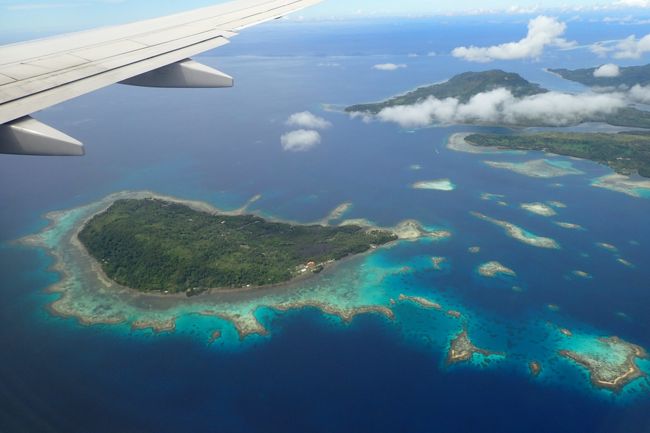 グアム発ホノルル行きで５つの島を経由するユナイテッド航空のアイランドホッパーというフライトが週に３便だけあるとのことで以前から乗ってみたいと思っていたのですが運賃と日程の兼ね合いで実現することが難しかったのですが、木曜日の勤務後に定時ダッシュ＋金曜日を有給にすることで週末旅行として今回ようやく実現することができました。ＵＡ１５５便の窓から見える海の色は自然色とは思えないような美しい青だったりで綺麗な海を沢山楽しませてもらえました。このアイランドホッパーの停車駅はグアム・チューク・ポンペイ・コスラエ・クワジャリン・マジュロ・ホノルルとなりクワジャリン以外は途中下車可能で駐機中に各空港の待合室に行くことができるのでそれぞれの島に足を踏み込んできました。以前、マニラ・パラオ・ヤップ・グアムを搭乗しているので今回はその続きの様な気分でした。<br /><br />グアムでは乗り継ぎ時間が６時間程度有ったので２４時間営業のＫマートに遊びに行こうと思っていたのですが雨が激しく断念で残念でした。空港の制限エリア外のベンチで何となく仮眠を取った後、制限エリアに入りラウンジで軽く食事を済ませてアイランドホッパーに搭乗しました。<br /><br />個人的には経由地のあるフライトは嫌いで過去に１ＳＴＯＰのフライトでペナン−クアラルンプール−香港（キャセイパシフィック）、クェート−アブダビ−シンガポール（シンガポール航空）を利用したことがありました。今回はどうしても乗ってみたくて好き好んで５ＳＴＯＰのフライトを利用しました。１ＳＴＯＰ、２ＳＴＯＰのフライトはよく見かけますが５ＳＴＯＰはなかなか珍しいのではないかと思います。このフライトを利用する人は他に手段が無いため仕方なくか飛行機好きかの２極端に分かれるのではないでしょうか。<br /><br />タイトルに載せた写真はグアムーチュークのチューク寄りで撮影した一コマです。