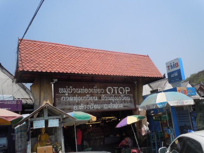 ランパーンへ行く道路沿いの「OTOP」のマークの看板がある、市があつた。<br />この「OTOP」とは「One Tambon One Product」の略である。<br />Tambonは「村」という意味と訳され「一村一品」ということになる。<br />タイの政府は国の地方開発、農村の自主自立、伝統の知恵の維持・活性を目的として、国内の各村々に最低でも1種類の主要製品を作るように推薦し、2001年にOTOPプロジェクトを始めていた。