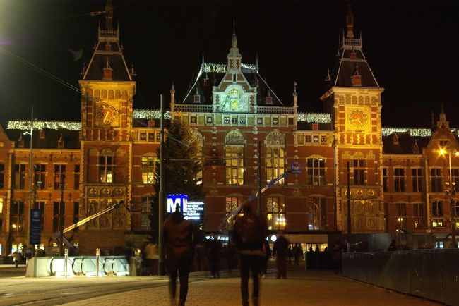 ２０１５年１２月、オランダ・ドイツ・ルクセンブルク・ベルギーを巡る駆け足ツアーに参加しました。<br /><br />第５回は、オランダの首都アムステルダムで夕食をとった後、中央駅からダム広場まで夜の散歩の様子と、国鉄に乗ろうとした時の顛末を紹介します。<br />せっかくアムステルダムに来たのに、美術館を見て、運河めぐりをしただけで、明日はもうドイツだなんてもったいない。せめて中央駅周辺の繁華街を散歩しよう。クリスマスマーケットもやっているはず。<br />ところがどっこい、オランダのクリスマス文化はドイツとは違いカトリックが多くないため、クリスマスマーケットも持ち回り。去年開催したからといって同じ広場でやるとは限らなかったのです。<br />空振りに終わったダム広場でしたが、ダムラックを歩けて満足です。<br />事件はホテルに帰る駅で起きました。あわや、ホテルに帰れない？という問題が発生。<br />その時、耳に飛び込んできた音は、救世主のたてる音でした。<br />今回の旅行記は、後半は鉄道編です。電車の券売機の使い方も紹介しています。