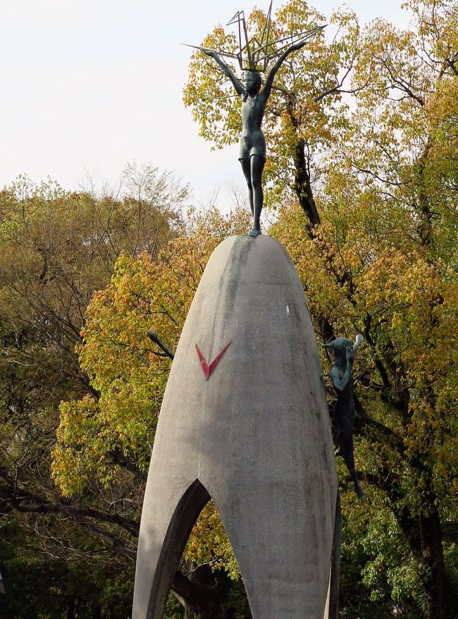 ■ 「原爆の子の像」の概要<br />○建立者 広島平和をきずく児童・生徒の会<br />○制作者 東京芸術大学教授 菊池一雄氏<br />「原爆の子の像」は、年間を通じて、たくさんの千羽鶴が捧げられていることから、別称「千羽鶴の塔」とも呼ばれています。<br /> 　像の高さは９メートルで、その頂上には折り鶴を捧げ持つ少女のブロンズ像が立ち、平和な未来への夢を託しています。側面左右の二体は少年と少女と明るい希望を象徴しています。像の下に置かれた石碑には、「これはぼくらの叫びです　これは私たちの祈りです　世界に平和をきずくための」という碑文が刻まれています。塔の内部には、少年少女たちの気持に感動したノーベル物理学賞受賞者である湯川秀樹博士の筆による「千羽鶴」、「地に空に平和」の文字が彫られた銅鐸を模した鐘がつられ、その下に金色の鶴がつるされ、風鈴式に音がでるようになっています。（この鐘と金色の鶴は、平成１５年（２００３年）に複製されたもので、オリジナルは広島平和記念資料館東館１階ロビーに展示されています。）<br /> この「原爆の子の像」の周辺には、折り鶴を捧げていただけるよう折り鶴ブースが設置されています。<br />平和記念公園内ではいたる所で、色鮮やかな折り鶴が見受けられます。折り鶴は日本の伝統的な文化である折り紙の一つですが、今日では平和のシンボルと考えられ、多くの国々で平和を願って折られています。このように折り鶴が平和と結びつけて考えられるようになったのは、被爆から１０年後に白血病で亡くなった少女、佐々木禎子さんが大きくかかわっています。<br />（http://www.city.hiroshima.lg.jp/www/contents/1110438305305/　より引用）<br />