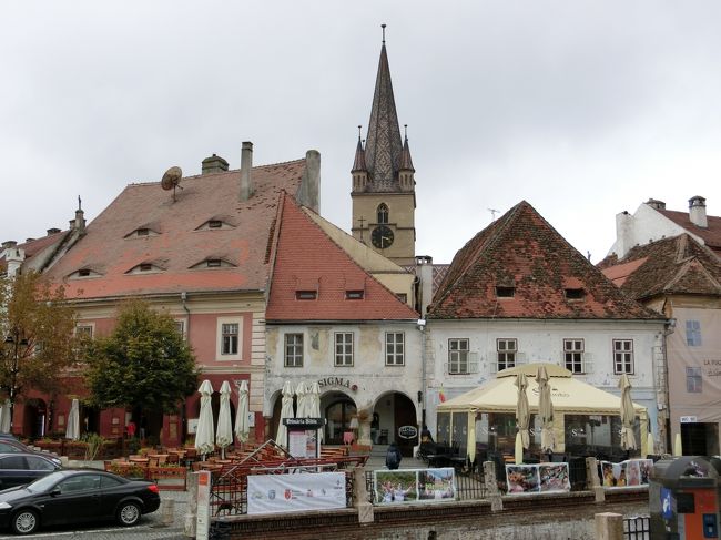 「小広場（大広場に隣接）」のある「シビウ」は「ルーマニア」の「トランシルヴァニア地方南部」の都市で「１１９０年」に「ドイツ人の入植者」によって設立され「１４世紀」には「商業の中心地」になった都市です。<br /><br />写真は「大広場」にある「三位一体教会の鐘楼」がのぞいている「小広場」です。
