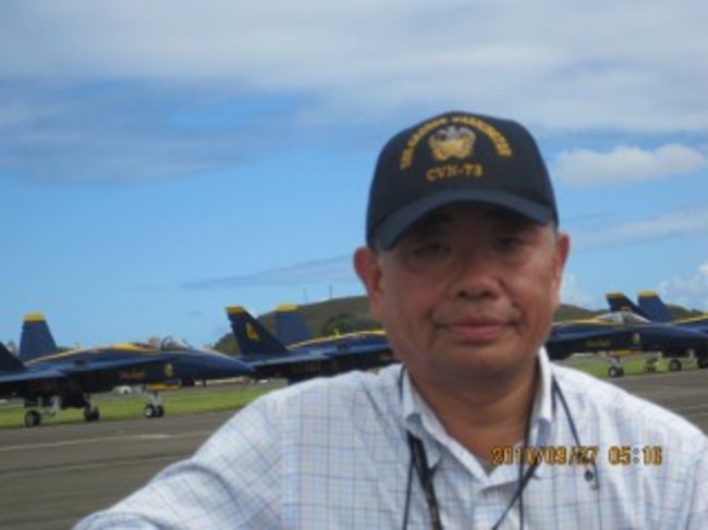 Blue Angels のFA18を背に私(オアフ島カネオへ海兵隊航空基地)<br /><br />ブログで動画を紹介してます。(2017.12.5)<br /><br />http://admpapa3tour.blogspot.jp/2017/12/blue-angels-120109.html?m=1<br /><br />ブルーエンジェルス。戦後間もなく誕生したアメリカ海軍の曲技飛行隊。私がこの存在を知ったのは小学生の時、フジテレビで放送されていた米国のテレビ番組「ジェットパイロット」。<br /><br />定年退職に近づき、余生が短くなるとやっておきたいことが一つや二つある。<br /><br />物造り屋の端くれとして航空宇宙に携わった飛行機大好き男にとっては、その一つがBlue Angelsの曲技飛行を見物することだ。<br /><br />この飛行隊は米国が日本に勝利した翌年、二ミッツ提督が作った64年の伝統がある。<br />目的は海軍のリクルーティング。<br /><br />米国本土ならばシーズン中、毎週末、何処かでショーが行われる。ところがハワイは毎3年。そこで私57歳、BAか2010年にハワイを訪れる機会を狙いハワイ、オアフ島、米海兵隊カネオヘ基地に見に行った。<br /><br />以下が帰国時に作ったサイトです。<br /><br />http://www.geocities.jp/blueangels2010_hi/<br /><br />ワイキキビーチからレンタカー(クライスラー)でカネオヘ基地迄は30分もかからない。ですが観客が皆様車で来ているので、ショーが終わってから基地を出るまで時間が掛かりました。<br /><br />飛行演技は流石に世界一である。<br /><br />やはり実物はビデオと違い迫力満点。<br />この日は雲が高くにあって、一部の演技が割愛されたのが残念でした。<br /><br />オアフ島独特の地形と風で仕方がないらしい。<br /><br />ちなみにこの時家族はワイキキの浜辺で楽しんでいました。<br /><br />観客席は有料の二等をインターネットで購入。飲み物、ランチボックス、耳栓、プログラム付き。<br /><br />地元の何世か判らない川崎ファミリーとそこで知り合いになり、帰国後、彼のプロ並みの動画映像の入ったDVD が贈られて来ました。<br /><br />貴重な宝物になっています。<br /><br />動画をお楽しみ下さい。<br /><br />https://youtu.be/4J1Typmeksk<br /><br />Admpapa3