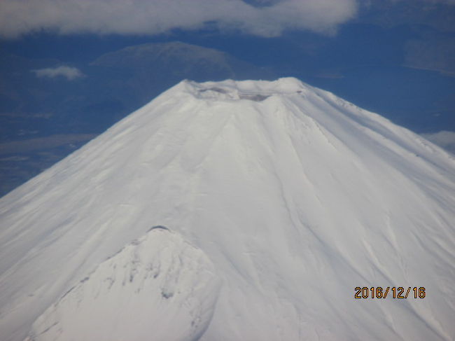 右手前方に丹沢山系・大山の登山道が見え、眼下に目を落とすと、どこの海岸か三浦半島のどこか綺麗な砂浜も見える。再び前方に富士山が傾いて見え、山はどんどん近づいてくる。真白の富士。白銀の富士だ。夏は黒鉄、冬は白銀。飛行機に乗る度、何回となく富士を見ているが、いつ見ても富士は神々しい。富士には神が宿る、と言われているが、間違いない。堂々と、どっしりとした富士だ。不二の神だ。世の中に二つとない神の山。<br /><br />過去自分は２回この山に登っている。百名山登山記録を確認すると、２００１年８月、最初に百名山を登った開聞岳と同じ年だ。この最初の年だけで、１９座の百名山を踏破し、富士山は１２座目に登っている。この時は単独行で、車で富士宮５合目登山口まで来て、そこから８合目の山小屋で眠れない夜を過ごし、未明に起きて山頂からのご来光を眺めた。感動の一瞬。日本一高い山から眺めるご来光だ。これほど神々しく、神聖な気分を気分を味わうことは過去余りないことだった。<br /><br />それから富士山山頂の火口を反時計回りにぐるりと一周、所謂お鉢周りをしたが、丁度その日は、富士山測候所の最終日で、白い丸いドームが解体され、ヘリコプターで運び去られる日だった。ここには嘗て新田次郎が作家になる以前、気象庁の職員、富士山観測所長としてこのドームに寝泊まりし、気象の観測をしていたのだ。<br /><br />その新田次郎がモラエスを題材とした「サウダーデ・孤愁」を毎日新聞に連載中、６８歳の若さで急死してから、既に２０年が経っていたが、彼の最初の小説「剛力伝」から始まる数々の山の名作は、彼自身が富士山測候所での数年間の経験が賜物していたに違いない。３か月前、羽田から同じこのコースを飛んで香港マカオへ向かったが、それは取りも直さず新田氏の息子さん、藤原正彦（現お茶の水名誉教授）が父親の死後３０年経ってから中断していたサウダーデの続編を完成させ、それを読んだ自分が去年はモラエスの終焉の地徳島へ行き、３か月前はマカオへ行き、又来年の１月には母国ポルトガルを訪問する契機にもなった。まさにこの富士を見ていると、新田次郎～サウダーデ～モラエスへと続く探訪の旅のきっかけとなるものだった。<br /><br />最初の富士山登頂から２年後の２００３年７月には、会社の同僚３人と今度は富士吉田口から登り始め、山頂の浅間神社前で静岡から登ってきた別の同僚５人と待ち合わせし、お互い手を取り合って登頂を祝福し、コッヘルで煮炊きしたラーメンその他の朝食を食べ、「神の池」の水を飲んでまた二手に分かれ下山したが、今この白銀の富士を見ていると、そうした様々な思い出が走馬灯のように走り去っていく。ほんの僅かな時間、時間にしたら１０分もないのだろう、右手に大きな火口を覗かせていた白銀も富士も、視界の後方に去って行った。<br />