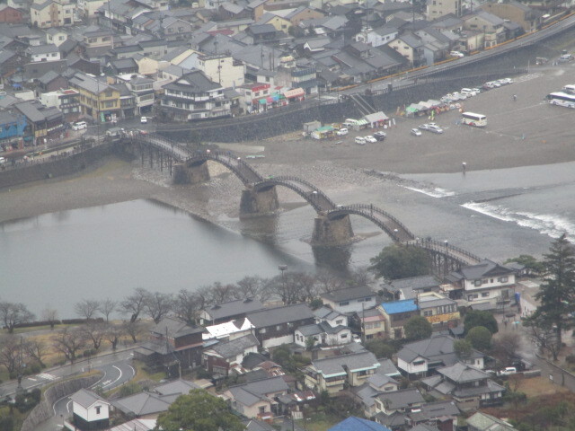 岩国城(いわくにじょう、山口県岩国市横山）は毛利元就の二男元春（もとはる、１５３０～１５８６）が吉川家を継ぎ、その二男で関ケ原合戦後出雲国月山富田城から移封された吉川広家（きっかわ・ひろいえ、１５６１～１６２５）が横山の頂上に造った山城で慶長１３年（１６０８）完成させますが、元和元年（１６１５）に『一国一城の令』適用を受けて廃城となり、以降麓の政庁にて藩政がなされた経緯があります。<br /><br />関ケ原合戦が起こる前、西軍の総大将に主家の毛利輝元（もうり・てるもと、１５５３～１６２５）を担ぐという石田三成の策に同心した安国寺恵瓊（あんbこくじ・えけい、１５３９～１６００）らの働きかけに反発した吉川広家は、輝元を説得して東軍に加担するよう働きかけるも実現できず、遂に内密で東軍に内応し毛利所領の安堵を取りつけ、同合戦では南宮山に布陣するも軍勢を動かさず、その為東軍勝利に貢献しますが、逆に西軍に与した各大名らは厳しく改易に処されます。<br /><br />戦後大坂城にて発見された西軍の数々の連判状には輝元の花押が散見され、責任追及せざるを得ずとして毛利家の本領安堵の密約は反古にされ毛利領は没収のうえ改易、そして同時に吉川広家に対しては周防・長門の二国を与えるとの沙汰が発せられます。<br /><br />これに対して広家は毛利本家の存続のため家康に対し起請文を提出した結果、家康から広家の願いを考慮して輝元に対して広家に付与されるはずであった周防・長門の二国を毛利本家に安堵する旨の起請文が差し出されます。<br /><br />かくして広家の働きかけによって改易を免れた毛利家は安芸国を中心とする山陽・山陰の１１２万石の大大名から防長二国の３６万９千石へと大幅減封を甘んずる事になります。<br /><br />防長に閉じ込められた毛利氏は長門国萩に新城を築き拠点とし、長府及び徳山を分家として支藩と認めるも岩国の吉川領については支藩とせずあくまでも家臣として扱われます<br /><br />上述の如く毛利本家からの冷遇に反して幕府からは江戸に藩邸を構え参勤交代も行われるという大名として遇せられ、更に岩国の地に築城が許されるに至り、吉川広家に対する厚遇ぶりが顕著であったがため以後の吉川氏の動きが微妙な立場となったようです。<br /><br /><br /><br />現地で入手したパンフレットでは岩国城の沿革について下記の通り記載されています。<br /><br /><br />「城下町岩国の沿革<br /><br />岩国地方には、平安末期に「岩国氏」と称する「平家」に属する一族がいて、相当の勢力をもっていましたが、寿永４年（１１８５）「壇ノ浦合戦」で阿蘇の地位を失いました。之に代わって勢力をふるったのが「弘中氏」で、鎌倉時代末期には周防国守護職であった「大内氏」の武将となっていました。しかし、弘治元年（１５５５）「厳島戦争」で毛利元就に敗れ滅亡しました。<br /><br />戦国時代末期、中国地方のほとんど（８か国３郡）を領有し、１１２万石の大大名となった「毛利氏」も、慶長５年（１６００）、「関ケ原の役」ののち、防長二国に減封され、出雲の国富田城（１２万石）にあった「吉川広家」も岩国３万石（のち６万石）に転封されました。吉川氏の家系は藤原氏の分かれで、もともと関東が地盤でした。「吉川氏」の始祖「経義」は駿河の国に始まり、正和２年（１３１３）５代「経高」は安芸国に移り、１３代２７１年の間活躍しました。<br /><br />なお、初代岩国藩主「吉川広家」は、サンフレッチェ（３本の矢）の教訓状を書いた「毛利元就」の子「元春（吉川氏の養子）」の三男にあたります。<br /><br />岩国藩は２７１年の間、藩政の方針として、文武両道の振興と人材育成、ン文化の向上につとめ、なお、２０００余町歩に及ぶ大干拓を行い、産業の振興、勤勉貯蓄の美風に努めました。<br /><br />この結果、岩国藩の石高は、幕末には実質１０万石以上と言われる程になりました。」<br /><br /><br />また同パンフレットにも「非運の岩国城」と題する説明文が掲載されています。<br /><br />「非運の岩国城<br /><br />岩国に移った「吉川広家」は、要衛の地横山の山頂に要害を、山麓に居館を築くことにし、慶長８年（１６０３）に山頂の起工式を行い、同１３年（１６０８）に岩国城が完成しました。横山の三方を迂回する錦川は天然の外堀で、川向こうに町割を行い、城下町が形成されていきました。<br /><br />緑の山頂にそびえる白亜の天守は、３層４階の上に物見を置くという、桃山風南蛮造りの山城で、藩の象徴として仰がれていましたが、元和元年（１６１５）、幕府の『一国一城令』により、完成からわずか７年で破却の運命に見舞われました。<br /><br />以来、山下の居館だけで藩政が行われました。<br />第２次世界大戦後、岩国城再建の動きが活発になり、昭和３２年には遠く「ハワイ岩国市人会」をはじめ、市民より多額の募金が寄せられ、復元されることになりました。<br /><br />　　　　　　　　　　起工　昭和３６年３月１２日<br />　　　　　　　　　　竣工　昭和３７年３月２１日<br /><br />再建された岩国城は、錦帯橋付近からの景観を考え、本丸南側に移動させました。」<br />