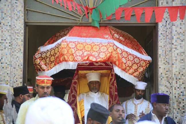 ティムカット際とは、イエスキリストが洗礼を受けたことを祝うお祭りで、年に１度、教会にあるタボット（アーク）が教会の外に出され、人目にさらされる貴重な日でもあります。<br />エチオピア中の正教会で行われ、アディスアベバ以外の都市でも行われている行事です。<br /><br />今日（１月１８日）は、ティムカット際の前日。各教会からタボットが搬出され、町を練り歩き、本祭の会場に運び込まれます。<br />今回は、マリアム教会からタボットが搬出される様子見学することができましたので、少しばかりお祭りの雰囲気をお届けできればと思います。<br />写真はマリアンヌ教会からタボット（真紅のビロードに包まれた司祭の頭上の物）が出された瞬間。<br />傘は大切なものを守ると言う意味とのこと。