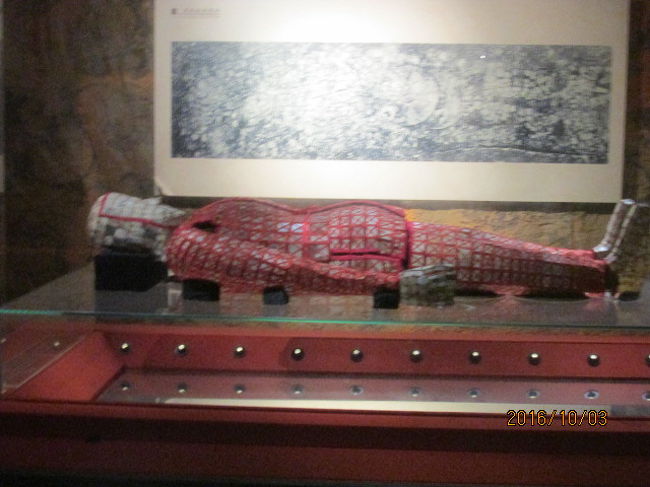 さてこれからいよいよ王のミイラが展示してあるへ部屋になる。先ず最初に目に着いたのは大きな棺だ。これは復元、複製された棺だが、極彩色な模様が描かれている。これも又黄泉の国の魔物除けになっているのだろうか。単に飾りとも思えない。エジプトや日本の古墳の場合は石棺と思うが、ここ中国では木棺だ。尤も日本でも平泉の金色堂のミイラは木棺に納められているので、一概には言えないか・・。<br /><br />かなり大きな棺桶で、王、それは南越王文帝に他ならないが、身長の高い、画体の大きな人だったのか・・。それとも防腐の為に何等かの薬剤を塗布され、更に布でぐるぐる巻きにされ、更にその上に玉器や宝玉、真珠などを分厚く重ねられて、元のサイズよりも何割増しに膨れ上がったからからか・・。そのミイラも又ダミーの複製で、新しいものだが、多分、忠実に復元されているに違いない。日本にも現存するミイラが何体かあって、羽黒山の木食上人など、どれも干からびた感じの、本当に人体のエキスと言った感じのものだが、この文帝王のミイラは、外観しか見えないものの、立派で威厳があり、絶対権力者を印象づけていた。<br /><br />この部屋の隣はビデオ映像室になっていて、２０００年前の時代のミイラの作り方、どれ程の財宝を費やしたかの説明、富の象徴、価値の高さ、等々、余すところなく情報開示、ＰＲに勤めていた。中国特有の事大主義、過大な自己宣伝とも思えない教育的な内用だった。博物館の順路表示に従って、中山王から始まって、最後に南越王のミイラまで巡ってきたが、充分、内容の濃いものだった。