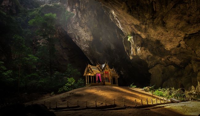 王室の保養地として名高いリゾート地ホアヒンから約70kmほど南下したカオ・サムローイ・ヨード国立公園内の洞窟に鎮座するクーハーカルハット宮殿は”タイで一番小さな宮殿”とも呼ばれている。<br />宮殿というよりは祠のような小さな建物ではあるが、頭上に空いた穴から射し込む太陽により洞窟の最奥に在りながらも燦々と映える光景はタイを代表する絶景として内外に知られている。<br />という訳で、昨年末あたりから気になっていたクーハーカルハット宮殿だが、自宅から現地までの移動を考えると面倒くさくて中々重い腰が動かなかった。<br />実はホアヒンはくろへいがパッカー時代に初めて沈没した町でもあり、通算の訪問回数は正直数えきれない。<br />クーハーカルハット宮殿のあるカオ・サムローイ・ヨード国立公園もホアヒンからバイクで7-8度は訪れている。<br />では、何故そんなにホアヒンが好きなのか？<br />と聞かれれば、熱弁をふるうだけの理由も見つからない。<br />正直ホアヒンのビーチは馬の糞だらけでタイで最も汚いビーチのひとつと思う。<br />珊瑚も無いので南国の白いビーチのイメージとは程遠く、ホアヒン（石頭）という町の名のとおり、浅瀬には岩礁が多く危なくて泳ぐ事もできない。<br />パタヤ近郊に住むくろへいとすれば、サメット島のある隣県のラヨーンの方が遥かに近くて美しい海が堪能できる。<br />自宅からホアヒンに行く為には、シャム湾をぐるっと半周しなければならず、距離の割には時間が掛るのだ。<br />その為、日本に住んでいたパッカー時代には頻繁に訪れていたホアヒンも、タイ東部に在住してからは2-3年に一度の頻度となった。<br />そこで、今回重い腰を上げた理由が<br />「スワンナプーム空港-ホアヒン直通VIPバス」の運行と「センタラグランデホテル」が格安で泊まれる。<br />の2点だった。<br />「センタラグランデホテル」はホアヒンを代表する歴史的なホテルであり、元々はタイ国鉄により100年ほど前に開業した。<br />当時のコロニアルスタイルがそのまま残る美しい木造の建物と、様々な意匠で創られた広大なガーデン。<br />パッカー時代にホアヒンで沈没していた頃は、近所の木賃宿に泊まりながら、垣根の向こうに広がる優雅な庭園ホテルを横目に周辺をブラブラしていた。<br />当時のくろへいは、垣根を隔てた僅か数十メートルの距離に絶対的な社会の格差を感じていたのだ。<br />純白のバスローブを羽織りながらプールサイドで読書を楽しむ白人ゲスト達が飲んでいる傘の付いたカクテル1杯の値段より安い木賃宿に暮らす貧乏旅行者からすれば、「センタラグランデホテル」こそが金持ちの象徴でもあった。<br />それから二十数年…<br />当時には無かったお金が今は少しだけある。<br />1泊3,800THBは今でも高いが、泊まれない金額ではない。<br />別に成り上がった訳では無いが20数年の月日を経て、ようやく垣根の向こう側に足を踏み入れる事ができたのだ。<br />という訳で今回の旅の目的は、<br />「貧乏人の積年の妬みを晴らして絶景まで見に行く」という壮大なものとなった。<br />まあ、あまり参考になるようなモンじゃないですが、写真だけは一生懸命撮ってきました。<br /><br />