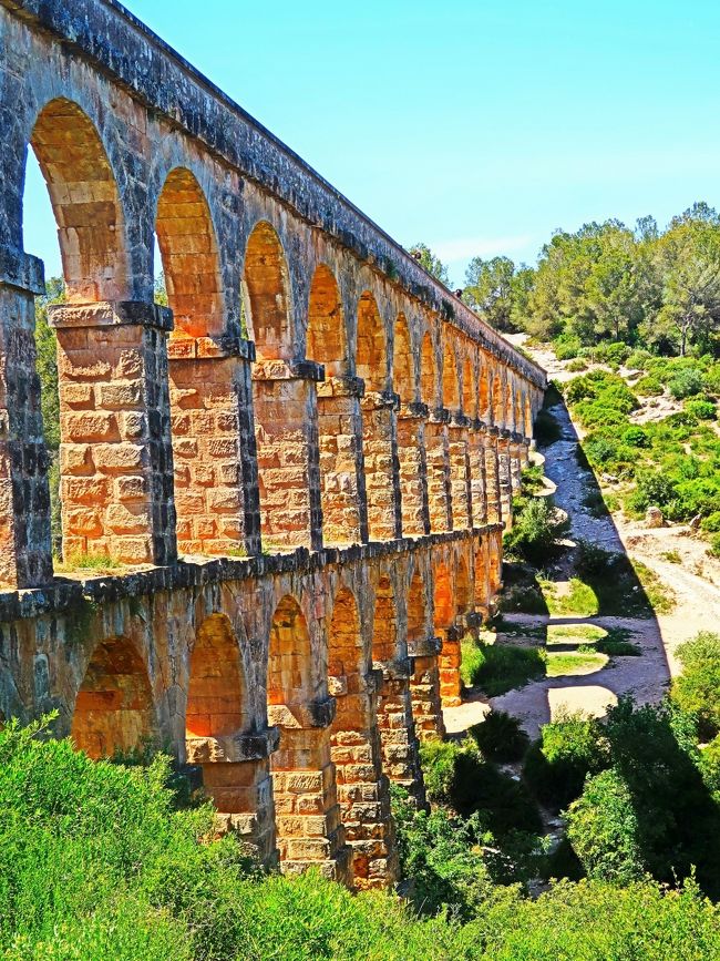 ラス・ファレラス水道橋はスペイン、タラゴナ郊外の山中にひっそりと佇む、タラゴナの北15キロにあるフランコリ川からタラゴナまで水を供給するためにローマ時代に造られた水道橋。<br />「タラゴナの考古遺産群」として世界遺産に登録されています。<br />かつては海抜92mの位置にあるラウレルエリアから10km以上続き、水道橋の上を北から南へと水が流れていました。石造りの橋は全長217m、高さ27m、幅2mあり、2層のアーチ構造で上は25のアーチ、下は11のアーチで支えられ、それぞれの柱の太さは1.8mもあり、スペインで現存する橋の中ではセゴビアの水道橋に次ぐ規模の橋です。<br /><br />紀元前1世紀のアウグストゥス帝時代に建造されたとされ、別名「悪魔の橋」と呼ばれました。この橋は当時の橋を作る技術では考えられないほど短い期間で建設され、「これは悪魔の仕業に違いない」といわれた伝説より悪魔の橋との異名がついたといわれています。<br /><br />橋の上には幅1mの水路があり、歩いて渡ることができます。高くて少し怖いですが、真っ青な空と緑に包まれた景色を眺めるのは壮観！<br />技術が発達していない頃、人の手でひとつひとつ積み上げられた橋を見るとセンチメンタルな気分になり、同時にローマ人が持っていた建築技術のレベルの高さに驚かされます。今でも2,000年前に造られた橋が崩れることなく残る堂々たる姿には無限の感動を覚えます。<br />（https://worldheritagesite.xyz/contents/aqueducte-de-les-ferreres/　より引用）<br /><br />スペイン北東部、カタルーニャ州の都市タラゴナの郊外にある古代ローマの水道橋。高さ27メートル、全長249メートル。2層のアーチ構造でアウグストゥス帝時代に建造されたと考えられる。2000年、タラゴナ市内の円形劇場、凱旋門などと共に世界遺産（文化遺産）に登録された。セメントなど一切使わず大型の切り石をくっつけて作られています。<br /><br />悪魔の橋と呼ばれる水道橋で、谷底から高さ27m！水を流した水路の部分が幅1mですが、ここを歩くことができます。もちろん無料です。<br />現存する部分は長さ217m、上を歩けるように整備されています。一番高い所で高さ25mあるそうですが、上の通路の壁が高いし幅もあるので怖くないです。　（https://matome.naver.jp/odai/2138271100566285101　より引用）<br /><br />タラゴナ（Tarragona）は、スペイン・カタルーニャ州タラゴナ県のムニシピ（基礎自治体）。タラゴナ県の県都であり、タラグネス郡の中心自治体。レウスなど近郊の都市を含めたタラゴナ都市圏の人口は約34万人。地中海に面した港湾都市で、物流の要所である。<br /><br />古代ローマ時代に築かれ、今でも水道橋や円形競技場などの遺跡が残り、世界遺産に登録されている。遺跡のために観光客も多く集める。近隣の都市としては、約80キロ東にバルセロナ、200キロ北西にサラゴサが位置している。<br />ローマ帝国の時代にはタッラコ（タラコ、Tarraco）と呼ばれ、ヒスパニア・タッラコネンシス属州の州都であった。5世紀に西ゴート王国の支配下に入った。8世紀始めにウマイヤ朝に征服され、町が破壊されたため、カタルーニャ地方の中心はバルセロナに移った。<br />（フリー百科事典『ウィキペディア（Wikipedia）』より引用）<br /><br />憧れのスペイン10日間　　（ルフトハンザ　ドイツ航空利用）<br />コース番号：E527A　　ブランド：トラピックス　総額　327,750円<br />3日目<br />09：00；ホテル発。<br />午前；バルセロナ市内　自由行動。<br />（　ピカソ美術館・カテドラル・カサ　ミラ・エル・コルテ・イングレス　）<br />その後、タラゴナへ（約98KM、約1時間30分）。<br />午後；【世界遺産】○ラスファレラス水道橋観光(15分)。<br />観光後、ホテルへ（約259KM、約3時間30分）。<br />19：00ホテル着。 <br />【宿泊地：マッサルファサール泊）】　 ●SHフロラザール <br />