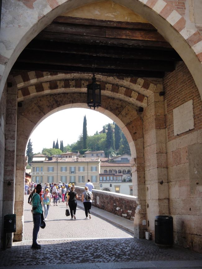 今朝も快晴で、迎えた“<ヴェローナ(Verona)>の“徘徊日和”であった。9時過ぎには『“の”字回りに、疲れるまで歩き周ろう!』って事で、ホテルを出た。今日は(2016.05.21の)土曜日の朝と言う事もあり一層散策する人も疎らとは言え・・・他人の目を気にする事も無い様子で、数少ない木陰ベンチを占有して、朝から一心不乱に?睦み合うアベック姿に・・・此処はイタリアだ!って改めて思い知らされながら、街を取り囲む<アディジェ川(Adige)>沿いで、清々しい川風を胸の奥深く吸い込みつつ・・・<スカリジェロ橋(Ponte Scaligero)>を背後にして、<ヴィットリア橋(Ponte Vittoria)>に向かって、遡上の歩を進めた。行き交う人もいない橋上では、のんびりと緊張感も一時解いて、ファインダーの先の素敵な景色に気を奪われていた時・・・何気に気付けば、いつの間にか傍らに来た“黒い大男”が「金をセビる」ではないか!?。無視しても一向に立ち去らず!堪らず、『ジャカましい!』って一喝したら・・・捨て台詞らしきもの残して、あっという間に何処かに消えて仕舞った。(スラレた等の被害はなかったが)仲々油断ならずの朝の一幕であったが、此処までの短い間に、『イタリアらしさの二つを味わった、“艶”と“厭”と』等と(独り合点しては)・・・「北イタリアの教会の内部装飾は、フレスコ画」と言われる通りの<聖エウフェミア教会(Sant Eufemia)>で沢山の古色画に囲まれた異空間に暫しの間身を安めた。中世の面影を宿し趣のある通りを(右に、左に)フラフラ、ブラブラと道行を楽しみながらの先には<ヴェローナ大聖堂(Duomo)>が現れて・・・更なる先の(写真スポットとして)多くのツアーが三々五々と集まり来たる(旧市街とサン・ピエトロ城を結ぶ)大理石の5連アーチの<ピエトラ橋(Ponte Pietra)>では爽快な開放感を味わった。更に、一際聳える70余mのレンガ色の塔に導かれる様に向かった先の、イタリアン・ゴシック様式の教会<サンタナスタージア教会(Sant Anastasaia)>の華やかな内部で・・・見つけ難い高所の「聖ゲオルギウスと王女」のフレスコ画は、何処に?柱の根元で「重そうな聖水盤を、肩と首で支えた格好の背むし男」の目立つ像を間近に観て・・・複雑な心持ちが去来した事が印象に残った。更には、非公開(個人所有)である<「ロミオの家」(Casa di Romeo)>の前を素通りし・・・<シニョーリ広場(Piazza dei Signori)>中央の「ダンテの像」に触れ・・・隣接する高さ84mの<ランベルティの塔(Torre dei Lamberti)>では、連れ合いが『(俯瞰)写真を撮りたい』と独りで上って行った。(<サンタマリア・アンティカ教会(Santa Maria Antica)>の側に在る)4角錐の屋根の上には騎士像が立ち、家紋等で華やかに飾られたゴシック様式の<スカラ家の廟(Arche scaligere)>の前は、燥ぐ少女達の賑やかさに包まれていた。。。