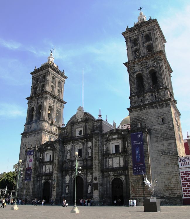 メキシコシティーから高速道路を使って３０００ｍの峠を越えてプエブラへ向かいます。峠越えのドライブインで噴火するポポカテペトル山と雪を頂いたイシュカシュワトル山を観ます。プエブラに到着後タラベラ焼きのお店訪問後カテドラルとサントドミンゴ教会訪問。ヴィラローサでランチバンキング後骨董品やお土産物屋の並ぶカエルの広場を通って砂糖菓子の家に、砂糖菓子の家は先日の地震で補習工事中で入館禁止でした。それからエル パリアン市場でショッピングタイムを楽しみました。バスに乗ってウェホツィンゴフランシスコ会の修道院を訪問しましたがここも地震のため入場禁止、屋外に設置されたクリスマスミサ用の祭壇を観ました。<br /><br />表紙はカテドラル（プエブラ大聖堂）です。