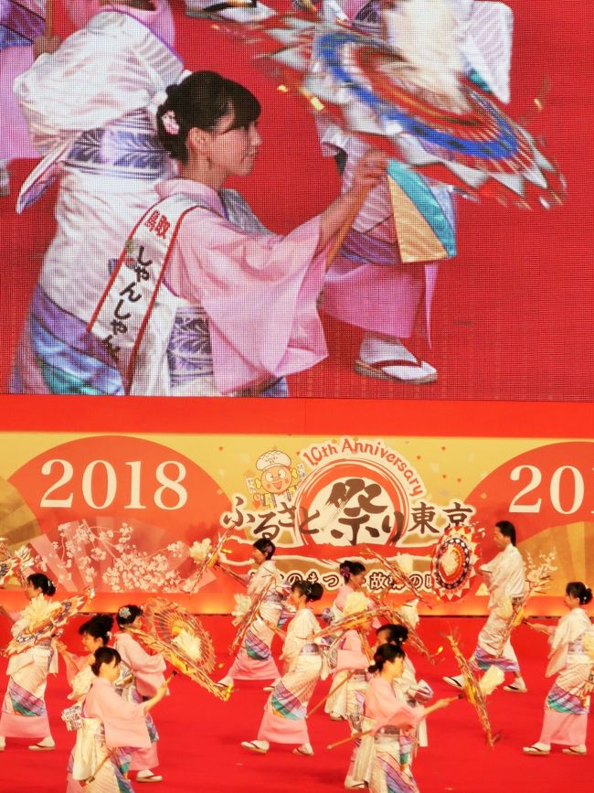 鳥取しゃんしゃん祭は、毎年8月中旬に鳥取市で開催される夏祭りである。<br />1961年（昭和36年）に始まった地元の神社の例祭の行列に、1965年（昭和40年）から鳥取市に伝わる伝統的な「因幡の傘踊り」を組み合わせて始まったもので、祭りの中心となる「一斉踊り」では、数千人の踊り手が傘を持って市内中心部を舞い歩く。傘に取り付けられた鈴が「しゃんしゃん」と鳴ることや鳥取駅前の鳥取温泉の湯が「しゃんしゃん」と湧くことからその名がある。<br />「一斉踊り」の参加者は100連・4000人あまりに及び、2014年に「世界最大の傘踊り」としてギネス世界記録に認定された。<br /><br />傘踊りは長さ1.2mの傘を振り回して踊る。踊り子自身の体や前後の間隔を考えると、少なくとも1.8メートル間隔になる。80人を5列に並べるとそれだけで道幅は最低でも7.2メートルになり、ルートに使える道路はかなり限られている。1連80名が5列に並ぶと少なくとも長さは30メートル、それに10メートル間隔で装飾車が連毎につく。1連あたり40メートルとして、4000人（50連）が並ぶとそれだけで長さが2キロメートルにもなってしまうのである。<br /><br />新たに導入されたのが「平成鳥取音頭」と「しゃんしゃんしゃんぐりら」である。この2曲では基本的に自由な振付で踊ることとされ、1曲で進む距離は従来の倍以上になった。なお、どちらの曲も従来の伝統的な振り付けで踊ることもできる。一方、かつて踊られた「吉岡小唄」や「白兎小唄」は使われなくなった。<br /><br />竹と和紙でつくられた傘には30から100個ほどの鈴と色とりどりの和紙の幣で飾られている。色にはそれぞれ意味があり、一番外側の紅白は「砂丘」、青は「日本海」、銀は「魚」、金は「賑わい」を表し、さらに赤と銀の組み合わせは祭りの華やかさや結束を表している。傘のてっぺんには雨乞いのための白和紙が立体的に取り付けられている。近年使われている傘は長さ1.2m、傘の直径は0.8mと、伝統的な「因幡の傘踊り」のもの（長さ1.6m）より一回り小さく、扱いやすいものになっている。<br /><br />1965年（第1回） - 第1回しゃんしゃん祭が開催される。<br />2014年（第50回） - ギネスブックにより世界最大の傘踊りとして認定。<br />1688名による踊りが成立したと認められ、「世界最大のアンブレラダンス」と認定された。この年は一斉踊りの総参加者は4200名、来場者は推定21万人を記録した。<br /><br />しゃんしゃん祭りは8月13日から延べ4日間と拡大されている。祭りの期間中には千代川の河川敷での花火大会、「すずっこ踊り」などが行なわれる。最大の催しは「一斉踊り」で、鳥取市中心街の目抜き通りである若桜街道、智頭街道、片原通りで数千人による傘踊りが行われる。<br />（フリー百科事典『ウィキペディア（Wikipedia）』より引用）<br /><br />■名称  ふるさと祭り東京２０１８－日本のまつり・故郷の味－<br />■開催テーマ   「日本のまつり・故郷の味」<br />■会期  ２０１８年１月１２日（金）～２１日（日）〔１０日間〕<br />■開催時間   １０：００～２１：００  ※２１日（日）は&#9369;：00閉場　<br />■会場   東京ドーム（東京都文京区後楽１－３－６１）<br />■主催   ふるさと祭り東京実行委員会<br /><br />ふるさと祭り東京　については・・<br />https://www.tokyo-dome.co.jp/furusato/<br /><br />鳥取しゃんしゃん祭　については・・<br />http://tottori-shanshan.jp/