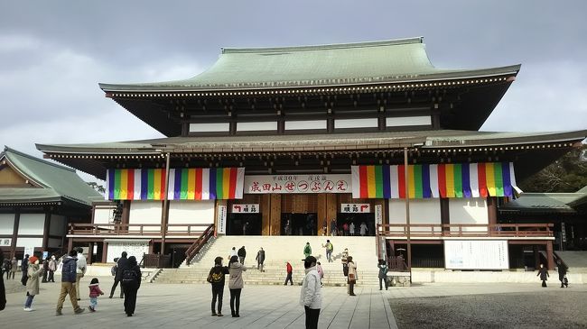 <br /><br />車には見慣れた成田山のお守りがあったのですが、気が付けば何年も経っているはずです。確か実家の親がお参りに行って、そのお土産としてもらったような記憶があります。名前は有名なお寺ですが、一度も行ったことが無かったので、お札を返して交通安全の新しいお守りに変えようと思いました。<br /><br />少しどんよりとした天気ですが、さすがに1月も終わりごろの平日ならば空いているだろうと出かけてみました。調べて見ると、お寺とは別に車と共に交通安全を祈願する祈祷殿があるようなので、そちらにカーナビをセットして走りました。成田市内に着いて進むと、カーナビの示す方向は交通規制で通れません。さらにお寺に近い駐車場は、長蛇の列でした。初詣はお正月だけかと思ったら、1月中は初詣として受け付けているのだそうです。護摩の時のお坊さんも、「新年おめでとうございます」と挨拶していたくらいですから。<br /><br />さすがに有名なお寺だと感心している暇はなく、カーナビ頼りに市内をウロウロして、細い住宅地の様な道路も抜けて、やっと交通安全の祈祷殿に着けました。周りの車にあわせて並び受付を済ませると、時間になって始まりました。始めに車のお祓い、そして本殿でお祈りと運転者のお祓い。終わると一人一人名前を呼ばれてお供物とお守りを頂きました。<br /><br />十分少々で終わったため、次は成田山新勝寺の大本堂へ向かいます。駅からお寺まで向かうのが表参道でしょうか。人通りの少ない横道から出て見ると、そこは大勢の人たちが歩いていました。商店も地元のお店が並び、外国人観光客もいてとても賑やか。昔からの地元の造り酒屋でしょうか。利き酒が出来たのですが、車のため味見が出来ずに残念でした。テレビでも紹介されるうなぎ屋さんは長蛇の列。整理券を発行していて、今からだと30分待ちですと言われました。もう一軒先へ行った物の、店頭で鰻をさばいて焼くところが人気なのでしょうか。諦めて、すぐお店に入れたお蕎麦の昼食になりました。<br /><br />新勝寺の総門を入ると、すぐにお札の納礼所と護摩の受付がありました。驚いたのは、納札所のつくりです。お札を変える所がベルトコンベアーになっていて、置くだけでどんどん奥へ流れていきます。それだけの規模のお寺ですし、返す方も多いのでしょうね。すぐ隣には護摩の受付があり申し込むと、まだ時間がるようです。境内の「釈迦堂」「光明堂」「平和大塔」と回りました。護摩は本堂に上がって「不動明王御真言」を唱えるのだそうです。大きく文字が書かれていて、「のーまく さんまんだー、、、」と言えるところだけ一緒に唱えました。御利益、御霊験が出来たのかなあ。その後に引いたおみくじは「大吉」でした。<br /><br />気分を良くして、羊羹をお土産に買い、家路に向かいました。<br />