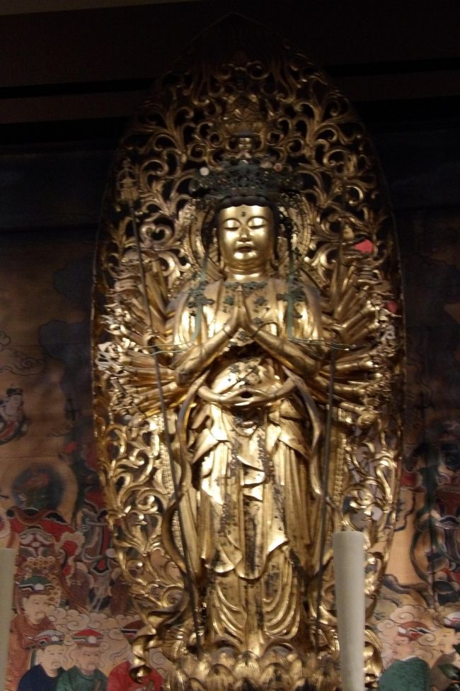 　上野の東京国立博物館（東博）で先月から特別展「仁和寺と御室派のみほとけ」が開催されているが、開会当日には金沢文庫に出掛けたために、上野へは足が遠のいていた。しかし、オリンピックの谷間で陽気が良くなるという予報だったので、上野へ出掛けてみた。<br />　今回の特別展は前回の特別展「運慶」よりも混雑している。それよりも、会場の案内係の女性がどうしようもないレベルの人に出くわしてしまったことを別にすれば、お寺側も主催者側もその気構えが伝わってくるような内容であった。<br />　最初に平成館に入ると直ぐに1Fの休憩所に行く。その入って直ぐの机にはお坊さんが2人座ってご朱印状を書いている。実は2Fの特設ミュ－ジアムショップにも700円で2種類のご朱印状を販売していたが、おそらくは、ご朱印状が出来上がるまで待つ時間やそれを受け取る瞬間も嬉しいものであろう。お坊さんに、「ご朱印状を書いているのですか？」と尋ねると、「要望が多いものですから。」という答えが返ってきた。また、「お坊さんと話そう」というコーナーも2Fにある。しかし、これまでも仏像が多く集められる特別展では朝夕のお努めをするためにそのお寺からお坊さんが来ていたことは何度かあるが、質問に応じることも少なく、いわんやご朱印を書いてくれたことなどは一度もなかったことだ。仁和寺（https://4travel.jp/travelogue/10435037）のお坊さんが東京・上野に来ることをないがしろにしていないことは理解できる。<br />　また、数年前からここ平成館2Fの特別展では写真撮影スポットが設けられることもしばしばあるが、レプリカの兵馬俑（https://4travel.jp/travelogue/11094230）だったり、茶室のレプリカ（https://4travel.jp/travelogue/11186536）だったりで今一の感じであった。しかし、今回の観音堂の仏像の展示には驚いた。実は観音堂とは思わずに、仁王門楼上の仏像か！と思ったのだ。案内係の女性に、何のお堂か尋ねたが、「仁和寺は広いですから。」と答える。「どこか聞いてきてもらえませんか？」「はい。」戻って来たので聞くと、「あ！そうか。」とすっかり忘れてしまっている。しかし、待っても彼女は戻ってこない。混雑の中で、たった1枚だけ「仁和寺　観音堂の群像について」という説明書を見付けて、観音堂であることが分かった。仁王門の群像ではなかったのだ。京都には山門楼上が極彩色に彩られた東福寺と知恩院の山門を何度か見たことがある。しかし、南禅寺の山門は何度が登ったが、徳川家の末裔か藤堂家の末裔でもないと中には入れないということで、廊下からは中は全く見えず、極彩色に彩られているのかどうかを気にしていた。南禅寺で修行していたお坊さんにも尋ねたことがあるが、覚えがないということであった。最近になって南禅寺のホームページを見ると、何枚もの写真は掲載されており、説明文にも「極彩色に彩られている」旨が記載されているが、それでいて写真はカラーなのではあるが、極彩色かどうかを判断できないようなものである。しかし、たまたま、仏像の本を買ったら、南禅寺の山門の写真が載っており、極彩色の綺麗な写真であり、南禅寺の山門も東福寺や知恩院の山門と引けを取らないものであることが分かったばかりであったからだ。<br />　再現された仁和寺観音堂の須弥壇や須弥壇裏や横の壁画は写真であろうが、仏像はレプリカではなく、本物だ。それを写真撮影できるのであるから、この撮影スポットが込み合うのも理解できる。実は奈良・春日大社の銅吊灯篭の本物を撮影スポットに展示した（https://4travel.jp/travelogue/11207822）ことがあったのだが、感動はなかった。今回は本当に感動できた。また、薄暗さが群像以外はレプリカであることを和らげているのかも知れない。<br />　平成館入館前に並んでいた時に隣のご夫婦のご主人から京都・広隆寺（https://4travel.jp/travelogue/10515055）の話が出たが、ここには千手観音坐像が何体もあって国宝になっている。いずれもバランスが取れた千手観音坐像である。今回の展示では3体の千手観音坐像（大阪・藤井寺、香川・屋島寺、徳島・雲辺寺）が展示されており、いずれも素晴らしいものだ。<br />　また、目を引かれる乾漆像がある。解説を見ると金沢文庫の龍華寺（https://4travel.jp/travelogue/10739376）からの出展ではないか！初詣に訪れ、本物は見ることが出来なかったが、この像の写真を2枚頂いてきたことがある。また、境内で御室桜（https://4travel.jp/travelogue/10541961）を見たこともある。仁和寺境内の御室桜（https://4travel.jp/travelogue/10433318）とは多少異なるようだ。<br />　勿論、仁和寺の数々の仏像も真近かに見られて、お寺では味わえないことである。また、少しは空いている時間を狙ってもう一度訪れるとしよう。<br />（表紙写真は観音堂の千手観音立像）