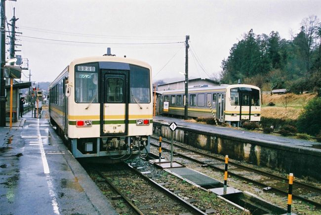 ≪2018.March≫あみんちゅ拝啓去り行くもの達への旅路その弐之④~頑張れ木次線乗車・そして帰り道編~<br /><br />平成30(2018)年3月31日に歴史を閉じる三江線。赤字路線が廃止されるのはJRという民間の営利目的の企業が取る方針として致し方ないところがあるように思えます。昭和62(1987)年4月1日の国鉄分割民営化後も行われてきた事実ではあるものの、なぜ三江線がこれだけ話題に上り、人が訪れるのか正直わからないところがありました。<br /><br />三江線がなぜ注目されるのか?勿論マスコミに取り上げられて多くの人々が知るところとなったことは事実です。それに加えて沿線住民の方々による三江線乗客に対する熱心な〝おもてなし〟が口コミで伝わった事実もあります。ただ〝陸鉄(時刻表上での行程作りを楽しむ鉄オタ)〟上がりの私としては〝ベストプラン〟が作れない鉄旅ゆえに夢中になってしまったことが大きいように感じています。<br /><br />運良く3月16日には木次線が復旧し、ついでに乗って来るという予定が完成し、旅立つことになりました。旅立つ前はバタバタするのがいつものこと。前日より早出残業をこなした後、疲れが抜けずに15:00迄寝た後に夜行バスで出発します。結局二兎を追う形は変えられなかったものの、完成した観光のない旅は他人には絶対に理解できないものという確信を持てるものとなりました。ファーストミッションの三江線往復は完遂できました。そして2日目はやはり中途半端な覚悟では乗ることのできない場所にあり、三江線同様冬眠の期間が取りざたされることが多い木次線に『頑張れ』の気持ちを込めて走破した後に、青春18きっぷを最大限利用して我が家へと帰る〝大移動〟のルートを辿ります。さあどんな旅路になったのやら・・・。<br /><br />【平成30(2018)年3月21日水曜日】<br />8:00の目覚ましで叩き起こされました。眠いのですがお腹が空いているために健康朝食バイキングを頂きにレストランへと向かいます。ゆっくり出発組のピーク時間に行ってしまったのか結構賑わっています。いつものように少しづつおかずを取って試食をしますが、濃過ぎず薄過ぎずの味付けは思いのほか食欲をそそります。まあ人目もあり適度に空いていたお腹を満たし部屋に戻ります。<br /><br />一息ついて出発し隣の出雲市駅に向かいます。悪しき習慣〝お土産〟を購入し、改札をくぐるのですがボケていたのか18きっぷに入鋏して貰うのを忘れてしまいます。そのまま米子行き普通列車に乗車し宍道駅で下車し、木次線に乗り換えます。運良く3月16日に冬眠から覚めた木次線だったので今回の旅に組み込むことが今回の旅の〝実現〟に繋がっています。<br /><br />ホームに停車している備後落合行き普通列車は2両編成でした。キハ120系の木次線色と一般色ですが、後方の車両には乗車することができません。からの車両を出雲横田駅まで回送し、折り返しの宍道行きとして運用されるものだということ。木次線カラーの車両はロングシートなのでボックスシートの車両に乗りたいのは山々ですが仕方がありません。しかし寝られないはずのロングシートで寝てしまうのが今回の旅の特徴。気がついたら西木次駅でした。そして木次線の名の謂れである木次駅に到着。しかし僅かな停車時間で出発します。ただ…この後一生の不覚をしてしまいます。亀嵩駅の出雲そばのことをすっかり忘れており買いに行くことを含め身動きすらできませんでした…。残念ですが仕方がありません。次回の楽しみにして乗り鉄旅を続けます。<br /><br />そして出雲横田で車両切り離しを含めて停車します。ただあいかわらずの冷たい雨模様なので積極的には動きたくはありません。駅舎を含めた景色をカメラに収め、再び列車へと戻ります。<br /><br />しばらく走ると出雲坂根駅に到着します。木次線と言えば出雲坂根と言われるほど有名なことですが、三段スイッチバックがある場所でもあります。20分程の停車の後逆方向に一旦進み、1km弱で再び進行方向が変わります。この区間には並走する国道314号線三井野原道路に〝奥出雲おろちループ〟なるものが存在し、その景色を列車からも楽しめるように徐行運転が行われます。多分天気が良ければ素晴らしい景色が広がっているのでしょうが、雨の中全てが霞んでおり眺望が望めません。天候だけはどうしようもないので、これまた次回の楽しみでしておくことにして列車に揺られながら先を急ぎます。そしてほぼ定刻通りに備後落合駅に到着し、はじめての木次線乗車の旅は終わりました。<br /><br />昔は乗り換えのために多くの人が行き交ったこの備後落合駅、かなりの賑わいがあったそうです。しかしSL +客車の時代からディーゼルカーの時代となり、加えて移動手段の車への転換によって利用客は激減します。宿も駅弁売りもなくなった現在、多くの利用客は乗り鉄か…という現状でした。適当な乗り換え時間があれば駅前でも散策するのですが、ローカル線の乗り継ぎには珍しく待ち時間がありません。木次線からの乗客はここで二手に分かれ、三江線乗車のために三次へと向かう者、そして私を含め帰路につくであろう新見方面に向かう者となります。半分以上は三次方面に向かう中僅かな乗客を乗せて1両編成の姫新線カラーのキハ120系は新見へと向かって出発しました。<br /><br />雨が降る中あまり景色は良くありませんが、三江線や木次線とは違う平坦な線路を走って行きます。途中の無人駅である備中神代駅までが芸備線、その後新見までが伯備線に属します。そして備後落合から1時間半程で岡山県北部の都市である新見に到着しました。<br /><br />既に16:00になっており、おまけに雨天のお陰で薄暗い感じを受ける新見。大阪からの高速バスが停車する場所でもありますが、正直なにもありません。駅前に真新しい〝祐清とたまがき〟の石像が置かれている以外は、三次よりも田舎かな?という印象を受けました。<br /><br />新見からは電車旅となります。津山を回り姫新線や津山線を利用する手段もあるのですが、乗り換えの関係で今日中に帰ることができないため伯備線を利用します。16:51新見発の三石行きの普通列車の前に16:37発の特急やくも22号岡山行きが先発します。381系車両は日本初の振り子式電車特急ですが、なんせ横揺れが酷く酔ってしまう方も少なくありません。その後改造や新造された電車に置き換えられて、現役ではこのやくも位になっています。でも私のルートだと出雲市発10:41、このやくも22号は14:33の出発とは…(笑)。<br /><br />特急を見送ると間もなく普通列車が入線してきました。入ってきたのはやっぱり…113系末期色塗装…。半自動ドア化されているために車内が暖かいのはありがたいです。定刻に新見駅を出発し高梁川沿いを下って行きます。単線区間もあれど上下線の交換のために長く停車することもなく進んで行きます。そして薄暗い中総社に到着し岡山圏に入ったことを感じます。そして倉敷を経て岡山に到着します。列車は三石まで向かいますが、食事タイムを取るためにここで下車することにします。<br /><br />この岡山駅ですが、政令指定都市となってから急速に発展した街だと思います。以前は新幹線停車駅ではあるものの…という記憶がありますが、今回下車してみて思いっ切り迷ってしまいました(泣)。40分という滞在時間は変わらないため、どんどん時間のみが過ぎて行き、結局マックでハンバーガーを食べて急いでホームに戻ります。<br /><br />赤穂線ホームに入線していたのはなんと213系でした。初代マリンライナーとして運行されていた車両ですが、赤穂線とレベルと言えばてっきり113か115系の末期色だと思っていたら、最近はワンマン化されたものも含めローカル線投入も進んでいるようです。休日の夜ゆえ結構な乗客数がいるようですが、座れない程のものでもなくちゃっかり一席確保します(笑)。赤穂線と言えば瀬戸内海を眺めながら鉄旅を楽しめる路線ですが、既に日も落ちており眺望はありません(泣)。岡山圏というのはどこまで指すのかは不明ですが、西大寺(岡山市)あたりから空席が目立ち始め、備前片上(岡山県備前市)あたりになると人も疎ら…という状態で電車は進み、終点の播州赤穂に到着します。<br /><br />敢えて夜の赤穂線を選んだか?と言えば、接続する新快速が播州赤穂始発だったというのが理由でした。しか~しそれは平日のこと、休日は姫路発となっていました。このあたりの予定は検討する要素もないので、漠然と見ていたため、休日ダイヤを見ていなかったというのが理由です。ただそこまでシビアにならなくてもいい区間だったこともあり、播州赤穂で2分間の接続で普通列車姫路行きに乗り換えて再び〝街〟である姫路駅に到着します。<br /><br />姫路では14分の接続なので、一服を決め込もうとホームの喫煙所をスマホ探すものの出てきません。昨年春に在来線で広島へと向かった際にはあったような気がするのですが、どうやら幻のようでとにかく改札を出て駅前の喫煙コーナーを探します。都市部になると分煙を通り越して禁煙ばかり進めるため、結局一部では心無いものの路上喫煙が行われています。そんなことはしたくないので場所を探すもののなかなかわかりません。それでも何とか見つけられたので数時間ぶりの一服を済ませ再び駅へと戻ります。<br /><br />播州赤穂から姫路もそうでしたが、大阪圏内に入ると車両が関西仕様となることがわかります。223系車両が投入された新快速米原行きが定刻に出発。21:00を過ぎていればさすがに姫路からの乗客は多いというほどのことはありませんでした。Max130km/hを誇る韋駄天列車新快速は、今日姫路まで乗ってきた列車とは比較にならない位の飛ばしようで加古川・西明石・明石・神戸・三宮・芦屋・尼崎に停車し、そして大阪駅に入ります。このあたりからは普通に滋賀まで行く方も多く、おまけにUSJ帰りと見える若い子達もたくさんいます。立ち客も出るくらいでしたが、新大阪・高槻と停車すると多くは下車してしまい、閑散となったものの京都から再び乗客が増えました。ここまでくると〝旅先〟という思いがなくなり、俄然元気が出てくる田舎者(笑)。山科・大津と停車し、我が街ターミナル駅に到着します。<br /><br />再び喫煙コーナーへと立ち寄ってから、いつものバス停へと到着し、最終バスを待つことにします。休日ダイヤの夜にはほとんどのバスが中型化された田舎の赤バス路線。その割には座席が埋まる位の乗客がいます。都会のバスの中型化は、運行頻度を上げるとともにノンステップ車両を投入するために使われるのですが、地元の赤バスは田舎仕様のワンステップタイプの中型車両。狭くて乗りにくい上に段差がある車両は、健常者からも評判が悪く、既に都市部では見かけなくなったものが普通に走っています。通勤時に乗る位では偉そうには言えませんが乗客の減少から廃止に至る、若しくはその候補に挙がってしまうような線区を乗ってきた後ゆえ複雑な気持ちもありました。そんな思いを持ったままバスは田舎の道を走り続け、ど田舎バス停に無事到着します。そして間もなく日が変わろうとする時間に自宅に到着し、今回の旅も無事終了します。<br /><br />出雲市~宍道~(木次線)~備後落合~(芸備線・伯備線)~新見~岡山~(赤穂線)~姫路~(山陽・東海道本線)~石山という今日の行程は459.1kmだったので、初日と合わせて935.5kmの乗り鉄旅でした。しばらく鉄旅はいいかな…なんて思ったりもした今回の旅路でした。<br /><br />《おしまい》