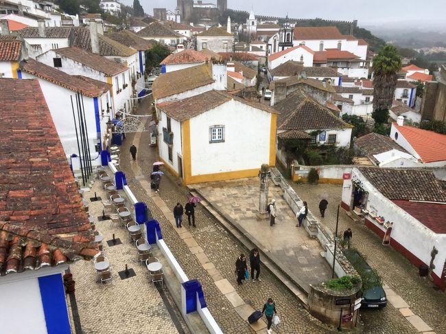 2018年1月5日（金）午後<br /><br />ポルトガル国鉄ＣＰのオビドス駅から坂道を登って行きました。<br />丘の上の町；オビドスに着くと、赤・黄・青のラインが入った白い建物が並ぶ街並みが印象的で、魅了されました(*^-^*)<br /><br />オビドスの街中ではサンタ・マリア教会やポルタ・ダ・ヴィラを観たり、ジンジャを味わったり、城壁の上を歩いたり・・・生憎の天気でしたが、満喫できました。ホント、天候さえ良かったら最高だったんですけどね(^_^;)<br /><br />昼過ぎにはオビドスを後にし、またもやローカル線列車でリスボンへ。<br />リスボン到着後は宿のあるロシオ地区を散策していました。