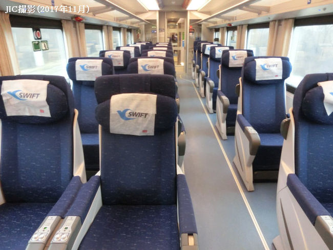 ■車内見学 ~バリアフリー用コンパートメントもある!<br /><br /> 最初の停車駅であるスモレンスクまで、まだ2時間ほどあるので、食堂車へ向かうついでに、車内の見学に向かう。<br /><br /> リュクス224号車・226号車・228号車の3両にはバリアフリー用コンパートメントがある。室内設備はリュクスと同じだが、障害者割引運賃の関係か、等級上は2等車の扱いになっている。シャワー、トイレもバリアフリー仕様になっており、車内用の車椅子も各シャワールーム内に備え付けられている。<br /><br /> 1等車はシャワーなし・トイレ共同の、昼は並列座席、夜は2段ベッドになる2人用コンパートメント、2等車は並列座席が向かい合わせになった4人用コンパートメント。1等車の座席とベッドの仕様はリュクスと変わらない。1等車のコンパートメント内には、洗面台が内蔵されたデスクが設置されている。2等車はリュクス・1等車に比べて背もたれが薄く、ひじ掛けも小さい。コネクティングルーム形式(2つの部屋が内部のドアでつながっている)の1等コンパートメントもある。<br /><br /> 2両連結されている座席車までたどり着いたところで、チーフパーサーを名乗る車掌に、丁寧な口調で、どうして写真を撮っているのか、と訊かれた。私は日本の旅行会社の社員で、この列車を日本人に紹介したいので体験乗車しているのだ、と話すと、空いているコンパートメントなら撮影していいですよ、と、快く応じてくれた。<br /><br /> 2等寝台車は3分の2くらい埋まっていたが、座席車は2両とも、その時は全く座っている人はいなかった。。新幹線のグリーン車並みの大ぶりなシートが通路をはさみ2席と1席ずつ並んでいる。向きはすべてモスクワ向きに固定されており回転しない。従って、ベルリン行きの場合すべて進行方向を背に向けることになってしまう。シートはシェル型で、倒しても後方のシートにせり出さない設計になっている。中央側のひじ掛けにオーディオサービスのジャックがあり、テーブルは反対側のひじ掛けに内蔵されている。天井から下がっている液晶モニターでは映画(ロシア語)が上映されている。