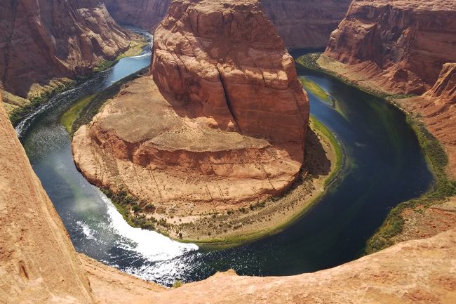 アンテロープキャニオンを見学した後はホースシューベンド(Horseshoe Bend)を見に行きます。<br /><br />ホースシューベンドはコロラド川が馬蹄形に蛇行して深い渓谷を作り出している場所。ガイドさんによると、最近急に脚光を浴びて来た観光地なのだそうです。<br /><br />断崖絶壁の縁まで行けるけれど、柵がないため転落には十分気をつけてくださいとのこと。皆が崖のそばまで行って写真を撮ろうとするので、他の観光客との接触や突風にも要注意です。<br /><br />この雄大な眺めは広角レンズでないと全景が写真に収まらないといいます。私のコンデジ(広角側の焦点距離24ミリ)では入りきるかどうかわからなかったので、スマホカメラと2台態勢で臨みました。<br /><br />駐車場から砂の道を歩くこと15分、腰を低くして恐る恐る近づいて見た崖の下・・・そこに広がっていたのは自然が創り出した驚異の眺めでした。<br /><br /><br /><br />~*~*~*~*~*~*~*~*~*~*~*~*~*~<br /><br /><旅行スケジュール><br />★印が本旅行記で取り上げた場所<br /><br />5月17日(木) 羽田15:15発デルタ6便でロサンゼルスへ<br /> サンタモニカ観光<br /> ラスベガスへ <br /> <ラスベガス泊><br />5月18日(金) アンテロープキャニオン観光<br /> ★ホースシューベンド観光 <br /> ★ <ペイジ泊><br />5月19日(土) モニュメントバレー観光<br /> グランドキャニオン ビューポイント観光 <br /> <グランドキャニオン泊><br />5月20日(日) グランドキャニオン朝日鑑賞<br /> セドナ観光<br /> ルート66ゆかりの街セリグマンに立ち寄り<br /> ラスベガスへ <br /> <ラスベガス泊><br />5月21日(月)~22日(火) ロサンゼルス11:02発デルタ7便で帰国