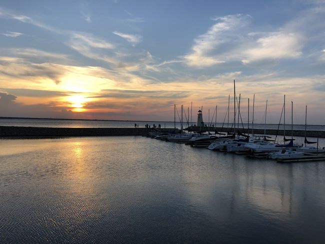 週末にちょっと時間があったので、ハフナー湖(Lake Hefner)に初めて行ってみよう!ということになりました。<br />偶然その日は午後6時くらいにNormanという街を出発し、6:30くらいにはハフナー湖に着いたのですが、<br />これがよかった!<br />オクラホマに長年住んでいる友達には「ヘフナー湖なんて何もないよ~」って言われていたのですが、<br />実際に行ってみると、レストランが3つほどありました。<br />メキシカンと、アメリカン(ハンバーガーとか)と、海鮮系のお店だったと思います。<br />グループで行き、メキシカンのお店に入りました。外の席に案内をしてもらい、メニューを注文。<br />まだ日が沈む前だったので、結構眩しかったのですが、サングラスをかけていたので、問題なく。<br />ちなみにここのメキシカンレストランのお店、一つの料理の量は結構あります!<br /><br />しばらく飲んだり食べたりして話していると、だんだんと夕焼けに。<br />これがすごくきれいで、フォトジェニックでした!<br />ヨットがいっぱい停まっているので、それがまたいい味を出しています。<br />食べ終わって、少し周囲を歩きました。<br /><br />そこに小さい灯台があります。<br />昼間みるとなんとも思わないような、本当に小さいものですが、<br />これが夜になると色々な色にライトアップされて、結構良いのです。<br /><br />そこで少し写真を撮って、また歩いて駐車場まで戻りました。<br />最初に友人から聞いていた話し等もあり、全然期待はしていなかったのですが<br />行ってみると実はロマンチックな雰囲気!で大満足でした。<br /><br />なので、行くのであればサンセット後をおすすめします。<br />それかレストランでゆっくりしつつ夜景を待つのもいいと思います。<br />昼間であれば、バイクレーンがあるので、サイクリングを楽しめるかもしれません。<br /><br />もし車で行く場合は、Lake Hefnerを目的地に設定するのではなく、<br />Hefner Parkwayにした方がよいと思います。<br /><br /><br /><br />