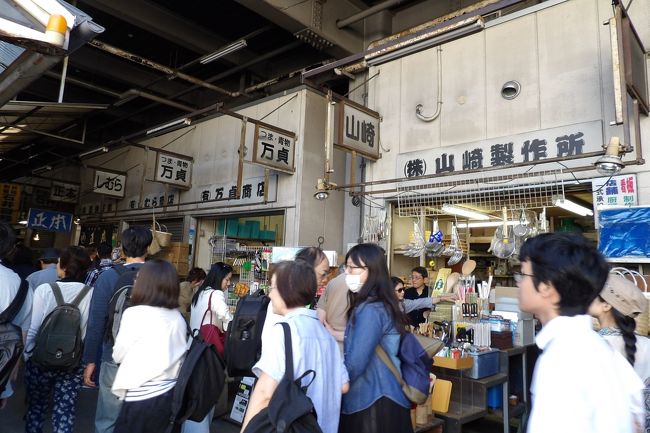 　もう1週間で閉場してしまう築地市場を最後に見ておきたいと思い、秋の長雨の中、1日だけの秋晴れの今日に訪れてみた。場内は平日にも関わらず混雑している。日本人よりも外国人の方が多いかも知れない。多くの寿司店前には行列ができており、通りには寿司店が軒を並べているので、列が重なり、通りを人が通るのが難しいほどだ。中には行列ができていない寿司店も幾らかはあるが、おそらくは（外国人向けの）ガイドブックに掲載されていない店であろうか。<br />　昭和10年（1935年）に開場した築地市場は構造の古さもあり、1970年代以降散発的に市場の移転が検討されてきた。移転する平成30年（2018年）までは実に40年以上も経ってしまっている。移転話が出ているのであるから、改築などはなされないために、東京都心部にある建築物としてはやはり驚くほどの状態だ。周りには朝日新聞社、東京国税局、国立ガン研究センターなど新築のビルが建ちならび、その中で戦前の施設が残っている訳であるから、とても都心で見られるような風景ではない。また、なぜか場外市場も都心らしい建物の店は「築地魚河岸」店くらいのもので、外に行列ができて込み合っている寿司店でさえも、都心にある店からは程遠い外見に見える。尤も、味は店の外観がどうのこうのということとは関係ないということなのかも知れない。それにしても資本を掛けないで上手い商売をして来たものだ。この場外市場にも、関東大震災後の復興店舗のようなトタン屋根の所謂バラック建築の2階建ての小屋で営業している店が何と多いことか。それでいて、観光地として内外から多くの観光客が訪れて、昼時には多くの飲食店（、多くは寿司店）の店の外には長い列ができる。儲かって当然と思われるが、店舗建物には大して投資はしていない。そのために他の都心の飲食街からは考えられないような外観の飲食街の姿を見せている。あるいは、どこの地方の観光地にある飲食街でもここ築地の場外市場よりは小奇麗で洒落ていよう。<br />　しかし、もう1週間もすれば、築地市場は無くなり、場外市場は単なる飲食街・商店街になってしまう。その時に他の飲食街・商店街と同じように素敵な飲食街・商店街にする必要を強く感じ、飲食街・商店街をもっと綺麗にしなくてはならないことを理解することであろう。そのはしりが「築地魚河岸」店であろうか。<br />（表紙写真は魚がし横丁）