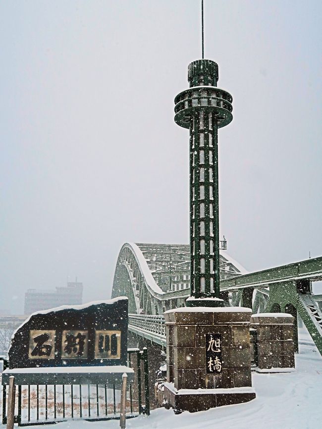 旭橋（あさひばし）は、北海道旭川市の石狩川と牛朱別川に架かる橋。 <br />国道40号（昭和通）の橋であり、かつては大日本帝国陸軍第7師団司令部に通じる道路として重要な役割を担ってきた。<br />戦時中には多くの兵士が旭日章の下を通って満州、ノモンハン、中国大陸、アリューシャンへと出征して行った]。軍都旭川を象徴する橋であったが、終戦とともに旭日章は撤去された。 現在は上下流にも橋梁があり、交通が分散されている。 <br /><br />旭川市を象徴する橋として「旭川八景」に数えられており、「土木学会選奨土木遺産」]、「北海道遺産」にも選定されている。また、豊平橋（札幌市）、幣舞橋（釧路市）と並んで「北海道三大名橋」と称されたが、現在ではそのうち旭橋のみが架橋当時からの姿を残している。 <br /><br />主要諸元型式 ブレースト・リブ・バランスド・カンチレバー・タイドアーチ橋橋長 224.82m　　　幅員 18.3m <br />竣工 1932年（昭和7年）11月3日　　建設 汽車製造（現・川崎重工業）  <br />発注 北海道庁旭川土木事務所  事業費 1,038,650円77銭<br />管理者 北海道開発局  <br />1927年（昭和2年）、北海道大学工学部長の吉町太郎一に設計指導を依頼し、「旭川のシンボルになる橋」と考えて内務省と協議した結果、橋梁形式にブレースト・リブ・バランスド・カンチレバー・タイドアーチ橋を採用することになった。 この構造では、トラス状に補強された二重のアーチ（ブレースト・リブ・アーチ）によって中央径間を大きく取り、そこに生じる下向きの力を、両側径間に張り出した片持ち梁（カンチレバー）を支持する上向きの力として利用することでバランスを取り、かつ中央径間では桁を（アーチのタイとして）張力を負担させ下路式アーチを構成して支点に生じる水平力を大幅に減らすことで、橋脚や基礎の構造を簡素化している。<br /><br />『旭川夏まつり』期間中は橋から放水やライトアップが行われ、『旭川冬まつり』は旭橋河畔会場でも行われる。旭橋周辺の河川敷は「リベライン旭川パーク」として整備されている。<br />（フリー百科事典『ウィキペディア（Wikipedia）』より引用）<br /><br />旭橋　については<br />https://www.hokkaidoisan.org/heritage_006.html<br /><br />国道40号  北海道旭川市から稚内市へ至る一般国道。 総延長 299.2 km  現道 250.0 km  <br />起点 旭川市　主な経由都市 士別市、名寄市  終点 　稚内市<br />（フリー百科事典『ウィキペディア（Wikipedia）』より引用）<br />