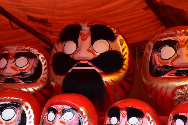 毎年旧正月（7･8･9日）に、吉原駅近くの富士市妙法寺で「毘沙門天大祭」が開催されます。<br />お寺の境内には、だるまを売る屋台が軒を連ね、だるま市としても賑わいます。<br />「毘沙門天大祭だるま市」は、日本三大だるま市のひとつとして数えられ、群馬県の高崎・東京都の深大寺のだるま市と並び、大勢の人が訪れます。<br />旧正月は毎年移動するため、訪れた2018年は2/22～24、今年2019年は2/11～13です。<br /><br />富士市吉原では江戸時代中頃に駿河半紙の原料であるミツマタの栽培が盛んでした。<br />やがて製紙業の合間に半端な紙を使って作りはじめたのが「だるま」。<br />このあたりのだるまは地名から「鈴川だるま」と呼ばれるようになり、だるまの生産地になっていった経緯があります。<br />鈴川だるまは「絵付けだるま」だけではなく、眉と髭に毛が生えているような「毛付だるま」があります。<br /><br />なお、旅行記は下記資料を参考にしました。<br />・開運富士毘沙門天HP<br />・LINEトラベル「日本三大だるま市！富士・妙法寺「毘沙門天大祭」」<br />・ふじのくに ささえるチカラ「杉山ダルマ店」<br />・子育てお出かけ生活 from Shizuoka「鈴川ダルマって知ってる？」<br />・富士市「製紙業の歴史」<br />
