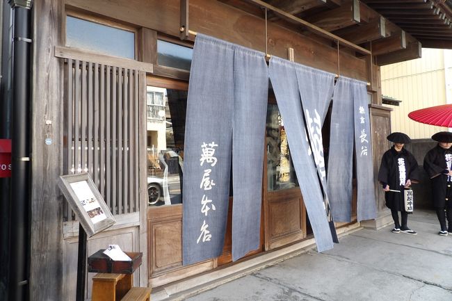 由比ガ浜通りには3棟の日本建築の建物が並んで残っている。通りに面した間口が同一であるからいずれも商家であったのだろう。その真ん中の商家は文化3年(1806年)創業の老舗商家「萬屋本店(よろずやほんてん)」であり、鎌倉では誰もが知っている酒問屋であった。しかし、平成18年(2006年)に酒問屋は店を閉めた。当時、萬屋本店の当主・石渡徳一氏は鎌倉市長であった。その10年後、萬屋本店をリノベーションして平成28年(2016年)にレストラン・結婚式場となった。Webには「築90年を超す母屋」とあるが、関東大震災(大正12年(1923年))後に建てられたものである。「大正ロマン」の文字も踊っているので大震災直後の大正15年(1926年)までに建てられたのであろう。建物と老舗商家「萬屋本店」の名を引き継いた客相手の古民家商売とはさすがに上手い商売のやり方だ。<br /> 昨今の古民家ブームの中、平成27年(2015年)春に、鎌倉三大洋館の呼び声が高い古我邸がレストラン・結婚式場に衣替えし、それが鎌倉での古民家ブームの火付け役となったのだろう。翌年にはここ「萬屋本店」が開店している。また、隣の古民家はレストラン「長谷 紫 - ゆかり -」に改装中(https://4travel.jp/travelogue/11467551)で今月(3月)14日に開店予定である。また、甘味処(https://4travel.jp/travelogue/11467407)や長谷寺参道の古民家カフェ(https://4travel.jp/travelogue/11467574)など、この3年くらいの間に古民家をリノベーションして開店したものである。<br /> 鎌倉幕府の開幕、滅亡、鎌倉公方の古河への転出、明治維新での廃仏毀釈、鉄道開通と鎌倉駅開業、古都保存法成立前夜。もしかすると鎌倉の今は、これらの転換期に肩を並べるほどの変革期を迎えているのかも知れない。<br />(表紙写真は萬屋本店)<br />