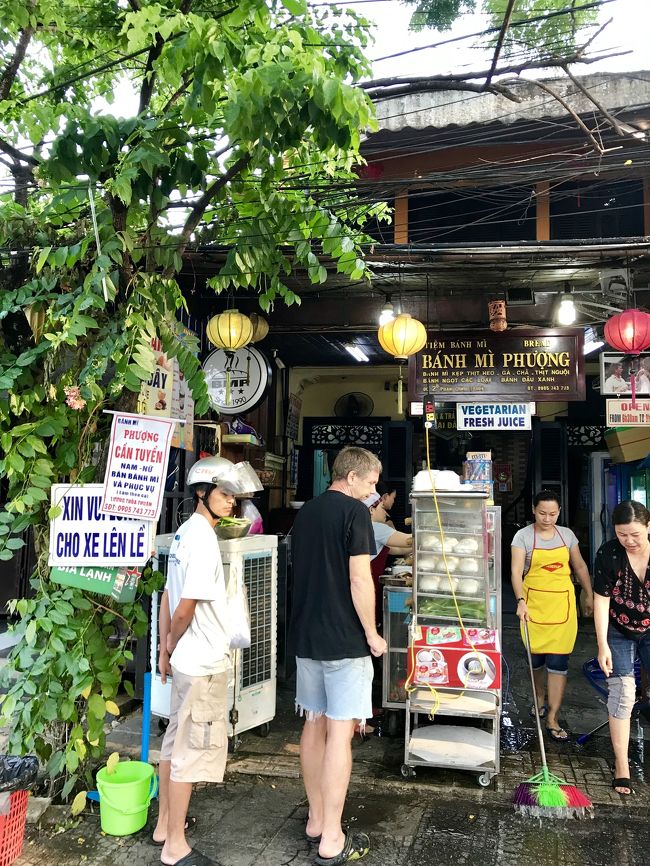 ベトナム旅行 2019.3<br /> ダナン→ホイアン→ダナン→バンコク<br /><br />私は何処へ行っても美味しいものを食べることを最重要視している気がします…。<br /><br />先導してくれる旅友さんは非常に貴重な存在です。<br /><br />地図の読めないオンナである私は、ホテルから徒歩圏内のこのバインミー屋さんにもおそらく自力ではたどり着けないでしょう。<br /><br />旅友ありがたや~~。<br /><br />バインミー ・フーン(フーンとフォーンの間みたいな発音)<br />昼間は恐ろしいほど行列しているこのお店も朝7時前に着くと、持ち帰りの先客2名のみ…<br /><br />まだお掃除中でした。<br /><br />初日は店内で食べます。<br /><br />この後ミーソン遺跡ツアーに行く予定だったのでちょっとだけ急いでホテルに戻らないと…です。<br /><br />旅行客が「バインミー 」と頼むと自動的に3番のmixedになるみたいです。<br /><br />それがおそらく「全部入り」ですね。<br />25000ドンは日本円で125円ぐらいです。<br />安っ!!<br /><br />飲み物は素早く出てきそうな13番のトラディショナル・ハーバルドリンクにしました。<br /><br />…スッキリしたミント系のアイスハーブティー。<br /><br />奥のテーブルに座ってバインミー が作られる様子を眺めます。<br /><br />わー美味しそう!<br /><br />ガブッとかじりつくと、バゲットがパリパリと美味しく、お肉と香草とスパイスも絶妙です。<br /><br />なぜかテーブルにはここを訪れたお客さんの証明写真が無数に貼られています。なぜ証明写真なのだろう…???<br /><br />いろんなお肉が入っていますね…<br />美味しい~~❣️<br />「世界一」と言われるのもうなずけます。<br /><br />このバゲット美味しいわ~。<br />買って帰りたいくらい…何処のパン屋さんのものなのかしら。<br /><br />ベトナム各地でバインミー を食べている旅友さんも絶賛で、「これは是非持ち帰ってみて違いを食べ比べてみたい」と。<br /><br />…で、翌朝再訪します。<br /><br />ホテルにはブッフェの朝食が付いているので、持ち込んで「ベトナムホワイトコーヒー」という甘~~いコーヒーを飲みながらいただきます。<br /><br />ホント、このスパイスが素晴らしいんですよね。<br />昨日はバインセオは入ってなかったと思うけど、今朝は入っています。<br /><br />素晴らしいお店でした。<br /><br />これと、フォー・リエンのフォーを食べるためにまた行ってもいいかなと思えるぐらい美味しかったです。<br /><br />牛肉のフォー<br />素晴らしい…<br />ああ、これが日本で食べられたらなぁ。<br /><br />夜店の屋台で食べたチェー(あんみつみたいなスイーツ)も美味しかったですよ。<br /><br />あー美味しかった❣️<br />ベトナムには美味しいものがいっぱいありました。
