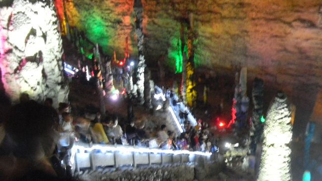 写真は武陵源の極彩色に照明された中国最大の洞くつ<br />黄龍洞の内部です。<br />洞窟の中は今日（２０１９年5月3日）も観光客で混雑していました。<br />しかし私たちは武陵源や、天門山の大混雑を経験して<br />いますので少しくらいでは驚かなくなりました。<br />慣れという経験は怖いですね。<br />極彩色に照明されている理由は分かりませんが洞窟内部は<br />大アミューズメント会場のようで娯楽性に富んだ空間でした。<br />武陵源に行かれたら時間の許せる方にはぜひ訪問されることを<br />お勧めします。<br /><br />黄龍洞（世界自然遺産）に関する旅行サイトがありました<br />ので次の通り一部を紹介いたします。<br /><br />「黄龍洞は、1983年に発見され、<br />その類を見ない規模と特異な景観で、<br />「中国一の鍾乳洞」と称されている。<br />張家界武陵源山脈・武陵源景勝地から<br />およそ5kmのところに位置する大きな鍾乳洞である。<br />他のカルスト地形と同様で石灰岩が地下水の浸蝕により<br />何万年もかかって形成された典型的な鍾乳洞で、<br />その全長は約60km余りもある。<br />洞内には気の遠くなるような年月をかけて大自然が創り出した<br />奇姿百態の鍾乳石が林立し、<br />他では決して味わえない独特の神秘な雰囲気を醸し出している。<br />なかでも一番の見所は、響水河、竜宮、天仙水、迷宮、海底神針等<br />がある。<br />洞内の観光に要する行程は洞内湖の遊覧船観光を含め、<br />総距離が約6000メートル、全部観光するのが約2時間ぐらいかかる。<br />一部分を観光しても、カルスト鍾乳洞の広さと偉さを充分に感じる。」<br /><br />スケジュール<br />○5月2日（木）武陵源バスターミナルから張家界へ１h、<br />　　バスで移動<br />（宿泊）Niuguanjia Modern Guest House（2日イン3日アウト）<br />『張家界牛管家現代客桟』ツイン<br />(ニウグアンジャー モダン ゲスト ハウス) CNY200（￥3,370）<br />空港からフリーシャトル、空港へは有料シャトル（30元）。<br />13F, Building 2, Hetianju Center, Yong Ding, 427000 張家界市<br />住所：張家界, 永定区, 禾田居中心2、13楼<br />(電話:+86 186 7442 3803)<br />　5月3日鍾乳洞見学<br />○5月3日（金）3週間前に2時間出発が遅れると連絡があった。<br />張家界空港、上海航空9344便23:20発、<br />上海浦東国際空港T1、01:25着