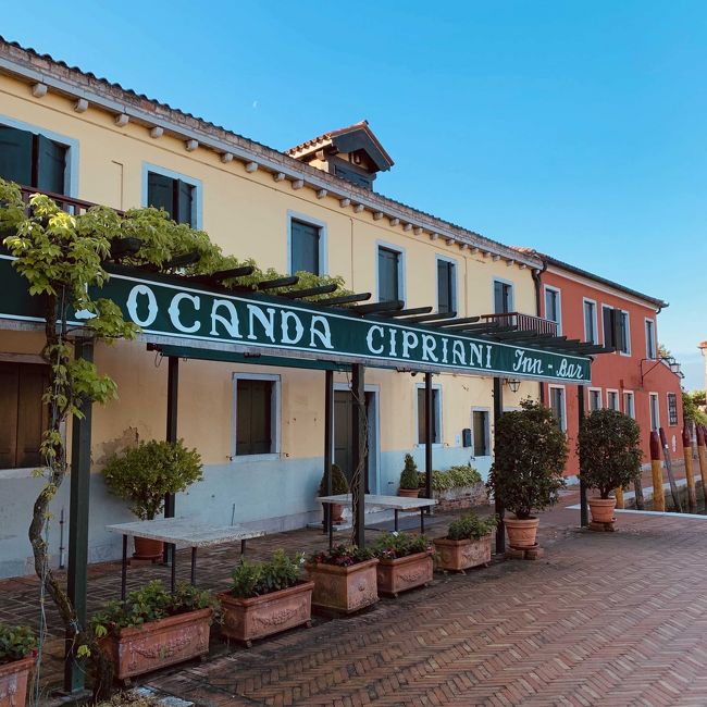 10連休をブチ抜いて、イタリアとポーランドに行ってきました。メインの目的は、ベネチアから100キロほど北東にあるウディネという町で開催される「ウディネ・ファーイースト映画祭」に参加することだったのですが、経由地がベネチアということで、せっかくだからベネチアにも何泊かしようと。さらに、エアラインがポーランド航空なので、帰りはポーランドにも何泊かしようと。かくして、平成→令和にまたがる13日間の旅が始まりました。<br /><br />ガイドブックやWebをあたっていると、ベネチア本島から少し離れた島にある「ロカンダ・チプリアーニ」という宿が気になりました。「6室しかない」「セレブ御用達」「宿泊料がそれほど高くない」ふむふむ。文豪ヘミングウェイやエリザベス女王、ダイアナ妃も宿泊したそうです。<br /><br />しかし、ヘミングウェイは世界中どこにでも現れていますね。キューバにもヘミングウェイの定宿や銅像を見たし、パリのホテルリッツもそうだし、行ったことないけどフロリダのキーウェストもゆかりの地ですよね。<br /><br />4月26日・27日の2泊、ロカンダ・チプリアーニの予約が取れました。ベネチア空港からロカンダ・チプリアーニに行くには、水上バスを乗り継いで行くか、水上タクシーで行くかの二択です。<br /><br />到着便が18:20、ホテルのレストランの予約が20:00だったので、迷わず水上タクシーに。しかし、これの運賃が驚きの160ユーロ(約2万円)!
