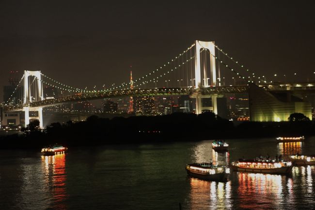 お台場からのレインボーブリッジの夜景 2019.8.17<br /><br />猛暑が続く中、お盆明けの十七日、わが家のシニア奉公人は午後からひまをもらい都内へ夕涼みに行ってきた。<br />2週間前には丸の内と銀座の夕方の景色を撮りに行ったが、今回は水辺を求めてお台場に行ってきた。<br />何年か前の年末にレインボーブリッジが虹色にライトアップされたのを見に行ったことがあるが、お台場はそれ以来だった。<br /><br />台場駅は「ゆりかもめ」の新橋寄りにあるが、小手指から行くには有楽町線の豊洲からでも行けるので、往きは乗換えが少ないそのルートを選び、帰りは新橋経由で地下鉄を乗り継いで池袋へ戻った。<br /><br />豊洲で「ゆりかもめ」に乗り換えるときに周辺に点在する比較的新しいビル郡を見渡したが、魅力を感じるようなものではなかった。<br /><br />「ゆりかもめ」の先頭車両の最前席は無人運転車両のため乗客用で、景色を眺めたり撮ったりするには最高!だった。<br /><br />台場駅を降りて駅前広場に着いたのは日没時刻15分前の18:15であった。<br />少し雲があったため、日が沈む光景は見られなかったが、周囲の建物に反射した残照はかすかに感じられた。<br /><br />お台場の人気スポットの一つである自由の女神像は、直射日光を受けない、写真写りがベストな時間帯で、大勢の観光客が入れ替わり記念撮影していた。<br />私も外人の家族に撮影を頼まれたついでに、自分のカメラで撮らせてもらったりした。<br />半数以上は外国人観光客のようだった。<br /><br />水辺に下りると子供に水遊びをさせている外人の家族が何組かいて、楽しそうにはしゃいでいた。<br />日没時刻から10分ほど過ぎると、空が次第に赤みを帯びて茜色に変わり、水面にも反射してすごくきれいな光景が見られた。<br />レインボーブリッジの手前に三々五々浮かんだ屋形船に灯がともり、次第に夜景へと変わっていった。<br /><br />18:50頃からは自由の女神像の照明の色が30秒間隔ほどで赤、青、緑、紫などに変化し、雰囲気もいろいろに変わった。<br /><br />東京港区とパリ市が連携協定を結んだことを示すエンブレム+ODAIBAのロゴが人気の記念撮影スポットになっていた。<br />https://www.city.minato.tokyo.jp/beieriasuishintan/event/20180522_pariskyoutei.html<br />この関連でフランス政府公式機関「アンスティチュ・フランセ日本」(旧名称:東京日仏学院)が案内テントを設けており、昔ここの会話専門コースで学んだことを話しメルアド登録をして福引(ゴロゴロ)を引いたら「日仏交流160周年」記念のボールペンが当たった。<br /><br />アンスティチュ・フランセ日本<br />2012年9月1日 - 東京日仏学院(Institut franco-japonais de Tokyo)、横浜日仏学院(Institut franco-japonais à Yokohama)、関西日仏学館(Institut franco-japonais du Kansai)、九州日仏学館(Institut franco-japonais du Kyushu)と在日フランス大使館文化部の統合により誕生。<br />Wikipedia<br /><br />しばらく撮影してからAQUA CiTY ODAIBAのレストラン街で夕食を食べに行ったが、目星をつけた店は並んでいる人が多く、妥協して入った店でも満足できてよかった。<br /><br />帰りの新橋行きゆりかもめはレインボーブリッジを通るが、乗っていてはまったく気づかなかった。<br />新橋からは地下鉄銀座線と丸の内線を銀座で乗り継ぎ、池袋から西武池袋線で帰宅した。<br /><br />撮影<br />EOS80D EF-S 18-135<br /><br />参考旅行記<br />虹色のレインボーブリッジと冬の桜 Rainbow Bridge/Sakura of Megurogawa in winter 2014.12.19<br />https://4travel.jp/travelogue/10963077<br />https://cdn.4travel.jp/img/thumbnails/imk/travelogue_pict/36/66/22/650x_36662224.jpg?updated_at=1419938676<br /><br />真夏の都心の夕暮れ 丸の内・銀座 (2019年8月4日)<br />https://4travel.jp/travelogue/11525209