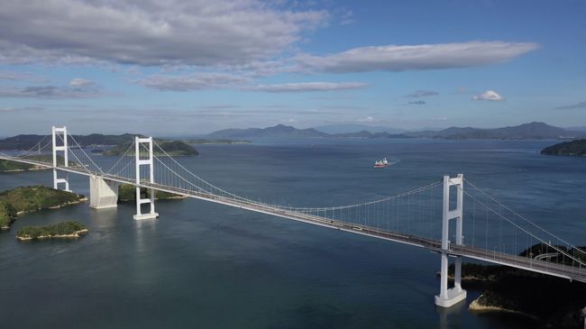 愛媛県の今治ICから西瀬戸自動車道「しまなみ街道」に入ると<br />まっさきに渡るのがこの来島海峡大橋。<br />3つの吊り橋が連続するのは世界でここだけ。<br />愛媛側からは第三大橋から第二、第一大橋と渡ることになります。<br />第一大橋を渡ると大島に到達し、そこから一般道に降りて<br />道の駅「よしうみ」をゲット。<br />そこからドローンに乗り換えて空から3連吊り橋を眺めてみました。<br />空からの来島海峡大橋、<br />青い海と青い空に真っ白な主塔が6本並ぶようすは圧巻かつ絶景でした。<br />しまなみ街道は、仕事やプライベートで何度も渡ったことはありますが今回、一番の感動でした。