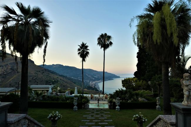 素敵な村、素晴らしいパノラマ、美しいビーチ、美味しいグルメをたっぷりと楽しんできました♪<br /><br />☆Vol.499：第16日目（7月1日）タオルミーナTaormina（メッシーナ県）♪<br />タオルミーナは標高200メートルの断崖上に広がる町でメッシーナ県に入る。<br />「Hotel Villa Paradiso Taormina」から予約してあるリストランテへ黄昏のタオルミーナの中を歩いて10分ほどでThe Ashbee Hotelに到着。<br />エントランスや庭園は大変美しい。<br />エレガントな雰囲気が広がる。<br />庭園からタオルミーナの北側へのパノラマが広がる。<br />長大な海岸が遠くまで続き、山並みも素晴らしい。<br />また、遠くにカラブリア州の山も見える。。<br />今夜のミシュラン1星リストランテ「St. George Restaurant by Heinz Beck」に期待が高まる。<br />ゆったりと眺めて♪