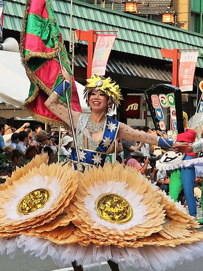 行く夏を惜しんで　浅草サンバカーニバル　東京中日スポーツ 　<br />　北半球最大のサンバの祭典「浅草サンバカーニバル」が8月３１日、東京都台東区の浅草寺周辺であった。華麗なダンサーらが息の合ったステップを披露し、観客を魅了した。<br />　パレードコンテストには、二つのリーグに計１６チームが出場。各チームが「忍者」や「チョコレート」などのテーマを設け、８００メートルのコースを４０分かけて思い思いに踊り歩いた。最高峰のＳ１（１部）リーグでは、地元・浅草の「仲見世バルバロス」が優勝し、４連覇を達成した。ほかに、地元小学生のサンバチームなども参加した。<br />　浅草サンバカーニバルは３８回目で、地元の人たちでつくる実行委員会の主催。毎年５０万人が訪れる。　2019年9月1日 <br />https://www.tokyo-np.co.jp/article/national/list/201909/CK2019090102000126.html#print　より引用<br /><br />浅草サンバカーニバル　については・・<br />https://www.asakusa-samba.org/<br /><br />エスコーラ・ヂ・サンバ・サウーヂは大道芸の街、横浜市野毛地区で1986年に誕生したサンバ・コミニティー。<br />SAUDEは「健康」「乾杯」の意。その名の通り、サンバを中心に据えた「人生の宴」 を体現する「娯楽の殿堂」を自負する。<br />ブラジルの伝統的なサンバ学校（通称、マンゲイラ）」 を指標とし、マンゲイラツアー、文化留学生を送るなどの交流を持つ。エスコーラ色もマンゲイラと同じ「VERDE e ROSA（緑色とバラ色）」で打楽器のスタイルもマンゲイラを踏襲。<br />浅草サンバカー ニバル30年連続出場。<br />エスコーラ・ヂ・サンバ・サウーヂについては・・<br />https://gressaude.com/<br /><br />浅草サンバカーニバル（Asakusa Samba Carnival）は、東京都台東区浅草で行われるサンバのパレード及びコンテストである。第1回は1981年に行われて今日まで続いている。日本で最大のサンバカーニバルのコンテストとして知られる。 <br />浅草サンバカーニバル実行委員会による主催で、毎年8月の最終土曜日に開催される。約50万人の人出がある。 <br /><br />S1リーグでは、リオのカーニバルになぞらえて、パレードの内容を審査員や沿道の観客によるモバイル投票などの採点方式により順位や優勝が競われる。<br />特にトップリーグであるS1リーグでは、エスコーラ・ジ・サンバ（略称：エスコーラ）といわれる大規模なチームによって順位が競われる。これら大規模なチームは、カーホ・アレゴリア（略称：アレゴリア）といわれる大がかりな山車を製作したり、ファンタジアと呼ばれる衣装をブラジルに発注製作したものを使用するなど、大規模に展開するチームが年々多くなっている。 <br /><br />毎年、各チームがEnredo（エンヘード。物語やテーマなどの意）を決め、それに基づいた楽曲や衣装、山車を製作し、それをパレードによって表現し、審査によるコンテスト形式で順位を競うからである。 <br />サンバにおけるパレードは、毎年チームで検討し選んだエンヘードのテーマが優れているか、またそれをいかに全体で表現するかを各チームで競うものである。またサンバパレードと言えば、露出度の高いダンサーが多いと誤解されているが、これも一部に過ぎない。タンガを着て踊るダンサーはパシスタやジスタッキ・ヂ・シャウン、ハイーニャなどと呼ばれるが、これらは少数のパートであり、一つのチームの中には、アーラといわれるパートのグループ分けがいくつもあり、ダンスやパフォーマンスなどいろいろな役割を演じるのが特徴である。 <br />（フリー百科事典『ウィキペディア（Wikipedia）』より引用）<br /><br />G.R.E.S.とは・・<br />日本でも本格的なサンバを志向する集まりが形成されるが、ブラジル本国の呼び方に合わせて、自らをEscola de Samba（俗にエスコーラと略す）と称するのが特徴である。エスコーラ・ジ・サンバは「サンバの学校」と直訳されるが、先生と生徒がいるようなアカデミックな「学校」ではない。近年では、さらにGr&amp;ecirc;mio Recreativo Escola de Samba（グレーミオ・ヘクレアーチヴォ・エスコーラ・ジ・サンバ、略称：G.R.E.S.）などと称すのが慣わしとなっている。「リクリエーション団体」を意味し、エスコーラ・ジ・サンバは地域に根ざしたコミュニティーの役割を果たしている。 実際は略称で表記・呼称されることが多い。 <br />（フリー百科事典『ウィキペディア（Wikipedia）』より引用）