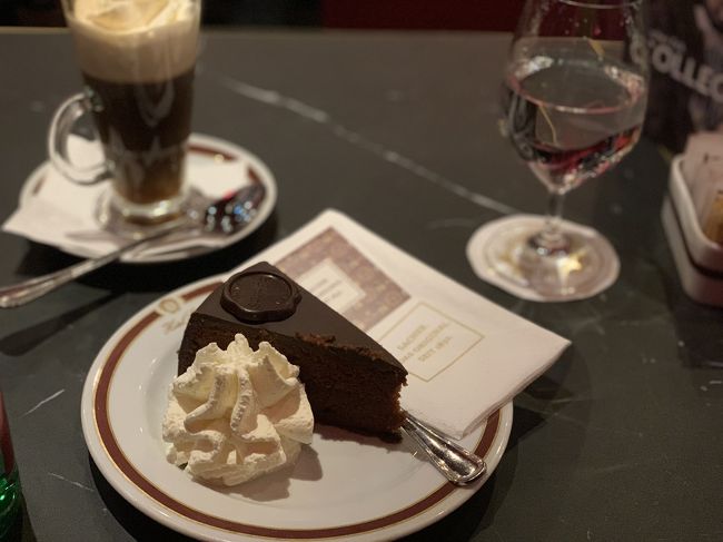 2月初旬に訪れたらウィーン。ザッハーとデーメルでザッハートルテの食べ比べをしました。<br /><br />実は「正統なザッハートルテ」を巡り、この2つの老舗の間で「トルテ戦争」なるものがあったことを知っていますか?<br /><br />その昔、王宮(ホーフブルク)近くにあったデーメルは王室御用達のお菓子屋さんでした。シシーの愛称で知られる皇妃エリザベードもここのケーキが大好物だったようです。<br /><br />一方、オペラ座やブルク劇場に近いホテルザッハーは音楽家やエンターテイナー達の集うカフェに。ザッハートルテは看板メニューでした。<br /><br />ところが1930年代、経営の傾いたザッハーの店はデーメルに助けを求めます。デーメルは助力の代わりに、自分の店でもザッハートルテを作ることを認めさせたのです。<br /><br />それでも自らのザッハートルテこそが「正統」だと信じるザッハーは、「オリジナル・ザッハートルテ」を標榜するデーメルに対して訴訟を起こしました。10年に及ぶ裁判の結果、二店舗ともザッハトルテを販売して良いが、「オリジナル・ザッハートルテ」の表示はザッハーに限られることになったそうです。<br /><br />オーストリア人の友達は、「ザッハーはいつも観光客でいっぱいだから私達はデーメルにしか行けないわ」と言っていましたが、実際にはどちらも20分ほどの行列でした。これくらいの待ち時間は日本人なら慣れっこですが、欧米人は待つのが嫌いなようでみんなイライラ気味でした。<br /><br />ヨーロッパの都市の中でも特に日本人に人気なウィーン。どちらのカフェでも多くの日本人を見かけましたが、デーメルではなんと両隣の席が日本人で少し面白かったです。<br /><br />さて、気になるザッハートルテのお味は。<br /><br />ホテルザッハーのザッハートルテはアンズのマーマレードが入っていて、甘酸っぱさが良いアクセントになっています。たっぷりの生クリームをつけながら食べると美味しいです。<br /><br />一方、デーメルのザッハートルテは純チョコレートという感じ。こちらの方がしっとりしていて、チョコケーキとしての美味しさが際立っている気がします。<br /><br />それにしてもどちらも人気店ということもあり高いですね。ザッハーでは、ザッハートルテ・任意のコーヒー・お水のセットで20€弱、デーメルでもザッハートルテとコーヒー合わせて15€程でした。<br /><br />オシャレなカフェが有名なウィーン。これは、ハプスブルク帝国時代にオスマン帝国がウィーン包囲を行った際にヨーロッパの中でいちはやくオーストリアにコーヒー豆が伝わったことが背景にあるそうです。<br /><br />今回の旅ではザッハーとデーメルの他にも色々なカフェを巡りましたが、一番驚いたのは、オーストリアでは、どんなに高級で行列のできているカフェでも、お店の人に席を案内してもらうのを待つのではなく、自分たちで勝手に席に座るのだということ。スタバやエクセルシオールのような大衆化したチェーン店のカフェなら分かりますが、レストランのようなカフェでもこうなのが意外でした。今回の旅でも最初のうちはお店の入口で棒立ちのまま、忙しそうに走り回る店員さんに不審な顔をされて恥をかきました(笑)