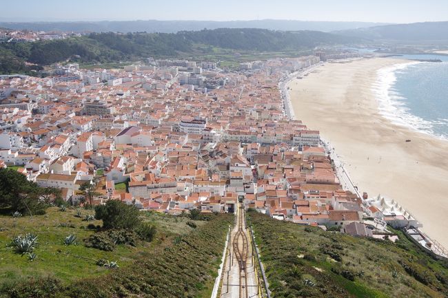 ２０１９年３月、ポルトガルを訪れました。<br />主な行程は、リスボンからロカ岬・オビドス・ナザレ・ポルト・アヴェイロ・<br />コインブラと周って、リスボンに戻り１日自由行動というものです。<br />　３回目は、リスボンを出発してロカ岬に向かいます。<br />ロカ岬は、ポルトガルの最西端、つまりはユーラシア大陸の最西端です。<br />『深夜特急』の最終目的地となった場所です。<br />次に向かったのは、城塞都市オビドスなのですが、とても素晴らしい場所なので、<br />敢えて後回しにして単発で旅行記にします。<br />今回はその次に昼食を兼ねて立ち寄ったナザレの町を紹介します。<br />ナザレもまたロカ岬のように大西洋に面した町ですが、こちらは完全なリゾート地。<br />レンガ色の屋根が並び、観光客相手の店が軒を連ねる町です。<br />ここの見どころは、この町を見下ろす丘の上からの展望になります。<br />町中からケーブルカーで上るのは最高です。<br />丘の上には白亜の教会や、ほんの小さな礼拝堂があり、<br />展望台からの眺めは本当に気持ちがいいです。<br />大西洋に来たんだなと感じる２つの観光地を紹介します。