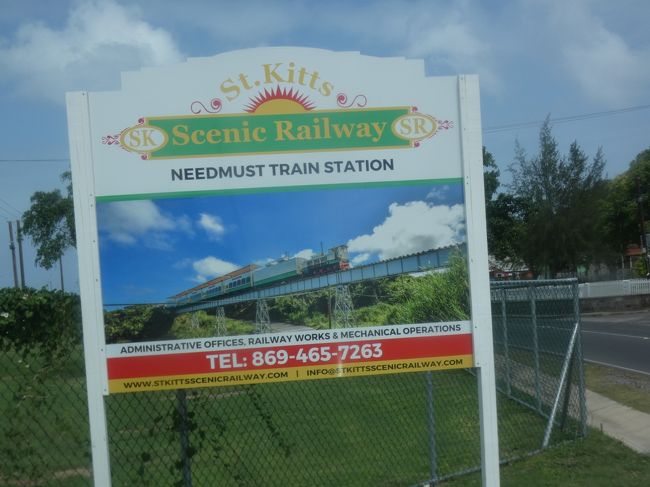 2020年2月19日(水)、今回の旅6日目、セントキッツ島(St. Kitts)観光。朝の10時からツアーで島の北側を一周中、10時45分過ぎに島の北西のラヴァレ(La Vallee)にある、セントキッツシーニック鉄道(St. Kitts Scenic Railway)の乗車駅、セントキッツエコパーク(St. Kitts Eco-Park)に到着。このパークは2011年に台湾との農業観光実証農場協力プロジェクトで造られた、農業とグリーンエネルギー、観光を共存させる施設(下の写真1)。セントキッツ・ネイビス(Saint Kitts and Nevis)は今や数少なく(15ヶ国)なってしまった台湾を国家承認している国の一つで関係が深い。<br /><br />セントキッツシーニック鉄道(St. Kitts Scenic Railway)は、首都バセテール(Basseterre)の北東部、空港に近いニーズマスト駅(Needsmust)からセントキッツ島の北東岸を回り、ここエコパーク駅までの29㎞を1時間半余りで結ぶ軌間762mmの狭軌鉄道路線。元々は1912年から26年に掛けて、農園からバセテールの製糖工場にサトウキビを運ぶために敷設された鉄道で、ラヴァレから南西岸沿いにも続き、この国の最高峰、標高1,156mのリアムイガ山(Mount Liamuiga)をぐるっと囲む全長約50㎞のループ線であった。<br /><br />この島には、イギリス領となって以降、最盛期には200を超えるサトウキビ農園があり、製糖工場もいくつもあったのだが、20世紀に入り利益が少なくなり、単一工場に集中する必要があり、工場と共に鉄道も造られた。サトウキビが収穫される2月から6月に掛けてのみ運行され、当初は蒸気機関車であったが、1950年代後半にディーゼル車に置き換えられた。この鉄道のおかげで他の島々が砂糖の生産を停止した後も生産は続けられ、1972年に工場は政府に引き継がれたが、徐々に採算が取れなくなり、2005年に政府は工場閉鎖を決定、同年7月31日で砂糖列車の運行は終了した。<br /><br />しかし、それに先立つ2003年の1月に政府と民間企業が協力してこの観光列車を立ち上げた。島の経済が砂糖で支配されていた時代の遺産を伝えるもので、スローガンは「西インド諸島の最後の鉄道(Last Railway in the West Indies)」。当初はループ線全線で運行していたが、2005年の砂糖列車の運行停止後に、主な顧客となったクルーズ客のフィードバックを受けて、現在の区間運行となった。現在使われているディーゼル機関車はルーマニア製で、エンジンはドイツ製。<br /><br />客車はアメリカ製で2階建て。1階には象眼装飾されたテーブルにクッション付きの籘椅子が置かれ、地元のアーティストによる絵画が飾られて、エアコン完備で2m足らずの巨大なアーチ状の窓からの景色を楽しめる。洗面所も設置されている。ただ、多分この日はそこまで混んでなかったので、みんな2階の展望デッキへ。パノラマビューを楽しみながら、ラムパンチやフローズンダイキリのフリードリンクを戴き、ライブパフォーマンスを満喫(下の写真2、3)。<br /><br />11時にエコパーク駅を出発するとまずはこの島に一番近い北北西約25㎞にあるオランダ領のシントユースタティウス島(Sint Eustatius)が見える。リアムイガ山の北東を回り込んでいくと大西洋。そのまま真っ直ぐ行くと、北大西洋を横断してイギリス。遥か遠い。海岸沿いの教会や墓地もいい感じ。山側にはかつてはサトウキビ畑が広がっており、古い製糖工場の跡がいくつも残る。<br /><br />時には高架鉄橋を渡りながら(下の写真4)1時間半ほど走ると、セントキッツ島の南端が見え、鉱山跡の前を通り、ニーズマスト駅に到着。再びバスに乗り1時前、クルーズターミナルに戻った(下の写真5)。<br />https://www.facebook.com/chifuyu.kuribayashi/media_set?set=a.4251580928245232&amp;type=1&amp;l=223fe1adec<br /><br /><br />ブリムストーンヒル要塞跡に続く。