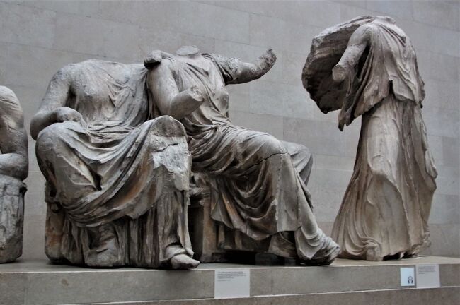 古い写真を見直すシリーズ。<br /><br />前回の「大英博物館（２０１３年）ーエジプト文明関係の展示ー」に続いて、今回はギリシャ文明の華、パルテノン神殿の彫刻展示を取り上げたい。アテネの博物館とこの大英博物館とで、彫刻や浮彫は、二分されているそうだ。私はギリシャには行っていないので、ロンドンやパリやイタリアにあるギリシャ彫刻類から抱くイメージしか浮かばないのだが、ギリシャ文明の彫刻類の完成度の高さは誰でもわかる。器楽音楽に関しては、楽器の進歩や楽譜の発明などから、後代のほうが、複雑な表現が可能になり、近代のほうが進展した部分があるように思うが、美術、それも石の彫刻などに関しては、様式の変遷などはあったとしても、ギリシャ時代にその技術は完成していたように思える。修正ができない石の彫刻は、粘土の像作成から鋳型をつくる工程とは比較にならないほど困難であろうことは素人でも想像できる。<br /><br />一枚目は、パルテノン神殿東破風彫刻の一部（デメテル、コレー、イリスの像－エクラン世界の美術より。）。<br /><br />（２０２０年１２月８日記す。）