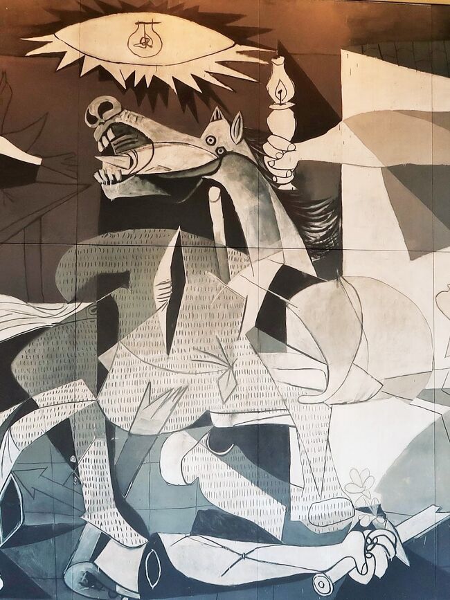 『ゲルニカ』（Guernica）は、スペインの画家パブロ・ピカソがスペイン内戦中の1937年に描いた絵画、および壁画である。<br />ドイツ空軍によってゲルニカが受けた都市無差別爆撃を主題としている。20世紀を象徴する絵画であるとされる。反戦や抵抗のシンボルとなり、「偉大な神が降りた」とも言われる。 <br /><br />1936年7月にスペイン内戦が勃発し、共和国軍とフランコを中心とした反乱軍が争った。共和国政府はピカソにパリ万国博覧会のスペイン館を飾る壁画の製作依頼を行った。ゲルニカがナチスドイツ軍によってゲルニカ爆撃を知り壁画の主題に選んだ。ピカソは絵画をスペイン共和国に無償で寄贈する予定だったが、材料費という名目で15万フランを受け取った。1937年6月末にはスペイン館に絵画が運ばれ、7月12日にはスペイン館の完成披露宴でこの絵画が公開された。<br />この絵画はなぜかスペインに送られることはなく、パリにあるピカソのアトリエに送り返された。1939年3月31日にはフランコ独裁政権が誕生した。 1939年9月には第二次世界大戦が勃発したため、そのままアメリカ合衆国のニューヨーク近代美術館(MoMA)に保管された。<br />1955年夏には18年ぶりにパリに戻って回顧展に出展された。回顧展の最重要作品としてパリ市民に称えられた。ピカソ自身は死去するまでに再び絵画を間近で見ることはなかった。<br />1975年11月にフランコが死去。1981年にはようやく絵画のスペイン返還が決定した。スペインでこの絵画は「故国の土を踏んだ最後の亡命者」とされている。<br />1992年9月、マドリード市内に国立ソフィア王妃芸術センターが開館すると、プラド美術館からソフィア王妃芸術センターに移された。絵画の両脇には非武装の警備員が配備されているが、絵画まで4mの距離まで近づくことができる。1997年にはスペインでもっとも入館者数の多い美術館となった。 <br /><br />画面全体には中世の三連祭壇画とギリシア神殿建築というふたつの異なる宗教美術の影響を見ることができる。時間や空間の超越を表現しており、宗教画的性格をさらに強めている。 <br />当時の絵画としては珍しくモノクロームで描かれているが、各部分の習作や後のタペストリー作品は彩色が施されている。徳島県鳴門市にある大塚国際美術館には絵画の実物大のレプリカが置かれている。<br /><br />美術史家の宮下誠は、全体として「キリスト教的黙示録のヴィジョン、死と再生の息詰まるドラマ、ヒューマニズム救済の希求、すべてを見抜く神の眼差し、それでも繰り返される不条理な諍いと死、人間の愚かさと賢明さ、人知を超えた明暗、善悪の葛藤の象徴的表現の最良の結果」を描いているとしている。ギリシア神話の怪物であるミーノータウロスは暴力、好色、平和など様々な象徴である。この絵画でも灯火を持つ女は真理を表すことがほぼ確実だが、社会主義の象徴であるとする研究者もいる。<br /> （フリー百科事典『ウィキペディア（Wikipedia）』より引用）<br /><br />大塚国際美術館は大塚製薬グループが1998年（平成10年）に開館した美術館で、西洋名画等をオリジナルと同じ大きさに複製し展示する陶板名画美術館である。 <br />延床面積は29,412m2。建築費や各絵画の使用料（著作権料）などを含め、総工費400億円。坂倉建築研究所が設計し、竹中工務店が施工した。 <br /><br />景観維持と自然公園法により、高さ13m以内とするために、一旦山を削り取り、地下5階分の構造物を含めた巨大な建物を造ったうえで、また埋め戻すという難工事を敢行している。 <br /><br />展示されている作品は、大塚オーミ陶業株式会社が開発した特殊技術によって、世界中の名画を陶器の板に原寸で焼き付けたものである。<br />作品は古代から現代に至るまで極めて著名、重要なものばかりを展示しており、これらを原寸で鑑賞することでその良さを理解し、将来実物を現地で鑑賞して欲しい、との願いが込められている。 <br /><br />陶板複製画は原画と違い、風水害や火災などの災害や光による色彩の退行に非常に強く、約2,000年以上にわたってそのままの色と形で残るので、これからの文化財の記録保存のあり方に大いに貢献すると期待されている。 この特徴を生かし、大塚国際美術館では写真撮影が一定条件下で許可されていたり、直接手を触れられたり、一部作品を屋外に展示していたりする。屋外の庭園に展示されたモネの『睡蓮』などはその性質を生かした好例である。 <br />（フリー百科事典『ウィキペディア（Wikipedia）』より引用）<br /><br />主な展示作品<br />世界25ヶ国・190余の美術館が所蔵する西洋名画1,000余点を、オリジナルと同じ大きさに複製し展示している （館内では「1,075点」と説明されている） <br /><br />B3F - システィーナ・ホール、スクロヴェーニ礼拝堂、フェルメールの部屋、聖マルタン聖堂壁画、聖ニコラオス・オルファノス聖堂、聖テオドール聖堂、貝殻ヴィーナスの家、エル・グレコの部屋、ポンペイの「秘儀の間」など<br /><br />B2F - モネの大睡蓮、バロック系統展示（レンブラント「夜警」など）、ルネサンス系統展示（ダ・ヴィンチ「モナリザ」「最後の晩餐」（修復前と修復後）・ボッティチェッリ「ヴィーナスの誕生」など）<br /><br />B1F - ゴヤの家、バロック系統展示、近代系統展示（ゴッホ「ひまわり」・エドヴァルド・ムンク「叫び」・ウジェーヌ・ドラクロワ「民衆を導く自由の女神」・ジャン＝フランソワ・ミレー「落穂拾い」など）<br /><br />1F - 現代系統展示（パブロ・ピカソ「ゲルニカ」など）　2F - 現代系統展示<br />陶板画の写真撮影はフラッシュ及び三脚使用禁止という条件で許可される。<br />（フリー百科事典『ウィキペディア（Wikipedia）』より引用）<br /><br />大塚国際美術館　については・・<br />https://o-museum.or.jp/