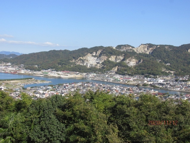 高さ凡そ３００ｍ程の屋島山上は平坦な土地になっていて、常の山にあるような峰、ピークと言ったものはない。午前中高松市街を間に置いた五色台にある霊場根香寺からこの島を眺めたが、それは実際来てみても分かることだが、卓状山地、テーブルマウンテンの形状をしていて、殆ど真っ平だった。屋島寺の前の駐車場はその形状を活かせて、広々としたものだ。大型バスでやってくる観光客向けなのか、大きな観光センター、土産物センターの建物も２カ所にあるが、内１カ所しか開いていない。その開いている土産センターもこのコロナ禍では閑古鳥。日本国中、観光業者は至る所カッコーの淋し気な鳴き声しか聞こえてこない。<br /><br />さて先刻この駐車場にやって来た時は、先を急いでいて右下の崖下に見える源平古戦場の跡をゆっくり見ることはできなかった。対岸の八剣山も横目でちらっと見ただけで、車を走らせてきたが、今は屋島寺の巡礼も終わり、少しだけ気持ちの余裕もできた。車をゆっくり走らせ、見晴らしスポットを探しながら、坂を下る。観光道路は部分的に道幅を広げ、何カ所かに古戦場跡の見晴らし台のスペースも作られていて、１－２台車を止めて眼下の景色を眺めているドライバー、家族などもいる。自分も車を止めて崖下の古戦場跡地を見る。見たところ、余り変わり映えのしない埋立地だ。ここが嘗ての戦いの跡とは、道路の案内板がなければ誰も想像はできないだろう。早鞆の瀬にしてもそうだ。古戦場跡の歴史は既に土地の中に埋没し、平家物語や歴史書の中でしか知りようがない。古戦場よりかその先の八剣山、庵治石を切り崩して取り出した、山肌が剥き出た荒々しい傷跡の方がむしろ興味を引いた。ここから切り出された大石は、船で大阪まで運ばれ、あの大阪城の巨大な石組みに使われたのだ。<br /><br />その大阪城築城の４００年ほど前、日本の歴史の中で数奇な運命を辿った平氏の栄枯盛衰があった。「平氏であらずば、人にあらず」とまで驕り高ぶった平家一門も最後は壇ノ浦、早鞆の瀬で海の藻屑のように消えて行った。清盛亡き後、源氏の荒武者に京都を追われた平氏一族は神戸福原に仮の都を移したが、そこも又義経を総大将とする追捕の軍に追われ、この地、屋島に逃げてきて、態勢を立て直しつつあったが、それも又義経の奇襲作戦により大敗し、ここから瀬戸内を遁走し、遂には壇ノ浦で清盛の妻時子に抱えられた７歳の安徳天皇は三種の神器と共に早鞆の瀬に身を投じ、平氏一族は胡散霧消した。<br /><br />兵庫一の谷では義経の突然の奇襲に多くの有力武将を失い、ここでも又、徳島経由で後ろの陸地から攻め立てられた平氏軍は一たまりもなく、破れてしまった。先刻屋島寺宝物館に那須与一遺族から寄贈された扇の的の屋島合戦図が展示されていたが、那須与一がこの戦場で勇名を馳せ、同時に平敦盛、佐藤嗣信も戦死した。それから程なく、この時の総大将義経自身が追われる身となり、奥州の地衣川にて無残な最期を遂げることとなった。芭蕉はこの地にはやって来なかったが、何故か屋島寺には芭蕉の奥の細道、平泉で詠んだ句「夏艸やつわものどもの夢の跡」の句碑が立っていた。一の谷には須磨寺があり、ここ屋島には屋島寺がり、壇ノ浦には赤間神宮がある。赤間神宮には耳なし芳一の墓もあり、今でも平家物語は語り継がれている。余り特徴の見られない、埋立地にしか見えない古戦場跡ではあるが、日本の長い歴史の中の一コマを記憶しているのだ。暫し眼下の波打ち際に目を落とし、平家の盛衰を思った。・・そう言えば厳島神社宝物館で国宝の平家納経を見た後、弥山に登り、丁度今の反対側の位置からこの瀬戸内を眺めたこともあったのだ・・。