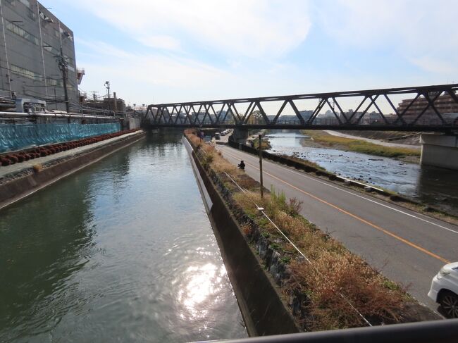 2020年12月10日(木)11時半過ぎ、鴨川に架かる塩小路橋の東詰から鴨川運河沿いを南に下がる。鴨川運河とは、琵琶湖疏水のうち丸太町川端の少し南の鴨東運河の鴨川への冷泉放水口から伏見丹波橋近くまでの8.9kmの区間の呼称。この区間は琵琶湖から冷泉放水口までの第1疏水・鴨東運河の工事が1890年(明治23年)に完成した2年後の11月に着工し、さらにその約2年後の1894年(明治27年)に完成した。<br /><br />京と伏見を結ぶ伏見街道(本町通)に沿って開削され、京阪本線が並行して走る。この京阪本線の全通(1915年)までは、旅客運輸が盛んだった。貨物運送も大いに利用されていたが、鉄道運輸の発展に伴い1935年頃にはほぼなくなり、戦争中に一時復活したが、1948年に蹴上インクラインの運転が停止され、1959年から60年に掛けて伏見インクラインや蹴上インクラインから電気設備が撤去された。1963年には四条付近の水路の上に駐車場が建設され、水運の機能は実質的に失われた。<br /><br />1987年の京阪本線地下化までは全て開渠だったが、現在は川端御池付近から塩小路通まで一部開口部はあるが、暗渠化されている。塩小路通の南側から出てくる水量は結構豊富。運河幅は約6mあり、結構広い。水深は1mから1.2m。鴨が優雅に泳ぐ(下の写真1)。<br /><br />南に向かうとまず潜るのがJR東海道本線(琵琶湖線)。1921年(大正10年)に開通したもの。東海道本線の京都から東部分は1879年(明治12年)に開通したが、1921年までは現在の奈良線のルートで南に下がり、稲荷駅から現在の名神高速道路のルートを大津まで辿っていた。その南に並行する東海道新幹線は1964年開通。どっちも飽きるほど乗ってる線。特に新幹線はここを渡るとようやく帰ってきた気分になる。<br /><br />線路を潜り、500mほど進むと一之橋。1924年(大正13年)に竣工した三角橋。三角橋は水運のためにかさ上げして架設されている橋で、橋の両サイドに階段があり、その形からこう呼ばれる(下の写真3)。一之橋から南は、左岸は三洋化成工業の敷地になっており、橋を渡って右岸に移る。<br /><br />一之橋の南側を鴨川から斜めに横切るのがJR奈良線の鉄橋。1879年(明治12年)に東海道本線として開通した部分。三洋化成の敷地を横切って京阪本線との連絡駅の東福寺駅に達する。この奈良線、多くの列車が奈良駅発着だが、奈良駅と奈良線の起点である木津駅の間は関西本線(大和路線)で、木津駅は京都府木津川市で、奈良線自体は全く奈良県を走ってない。<br /><br />運河の右岸(西側)の道は師団街道(表紙の写真)。かつて深草にあった陸軍第16師団に因んでこう呼ばれる。第16師団の設置に伴い、1911年(明治44年)に京都市街から師団司令部に至る国道として指定された。終戦後は国道24号に指定されたが、1971年に国道24号は竹田街道に移った。その竹田街道の東に位置し、京阪本線の西側に並行する。北は塩小路橋東詰で川端通につながり、南は国道24号を越えて京町通につながる。塩小路橋東詰から十条通までは鴨川運河の右岸を走る。<br /><br />師団街道から九条跨線橋上への交差点に続く道へ分かれる三差路(下の写真4)に橋台のみ残るのが岸上橋。かつては向かいの三洋化成工業の通用口に通じていた。これも三角橋。橋の名前はこの辺りの住所が福稲岸ノ上町から来ている。<br /><br />三洋化成は紙おむつに使われる高吸水性樹脂を世界で初めて工業生産した会社で、界面活性剤やウレタン樹脂、特殊化学品などを開発・生産しており、1949年にこの地で創業、現在も本社、研究所、京都工場がここに置かれている。申し訳ない、京都に40年以上いるけど、初めて知った。<br /><br />ちなみに、九条跨線橋へ連絡道路は2020年3月末に供用開始された道で、出町柳から十条通までを結ぶ鴨川東岸線の整備の一環として架橋された。高架橋の上に新たな交差点が造られ、九条通から川端通や第二京阪鴨川東ランプ、稲佐山トンネルとのアクセス性が向上した。なお、自転車や歩行者は通れない。<br /><br />三洋化成工業の南、九条跨線橋を挟んであるのが二之橋と柿本橋。九条跨線橋の上は九条通で、京都市の主要な東西の通りの一つ。平安京の南端の九条大路にあたる。跨線橋の東はJR奈良線と京阪本線を越えて東福寺交差点でそのまま東大路通につながり、西は鴨川を越え、九条河原町交差点となる。1937年(昭和12年)に架設されたもので、1978年9月末の京都市電最後の日までは九条線が中央部を走っていた。二之橋は1993年、柿本橋は1994年に架橋された新しい橋。柿本橋の名前は右岸の地名、福稲柿本町から。<br />https://www.facebook.com/media/set/?set=a.6035166139886693&amp;type=1&amp;l=223fe1adec<br /><br /><br />さらに南に進むが、続く