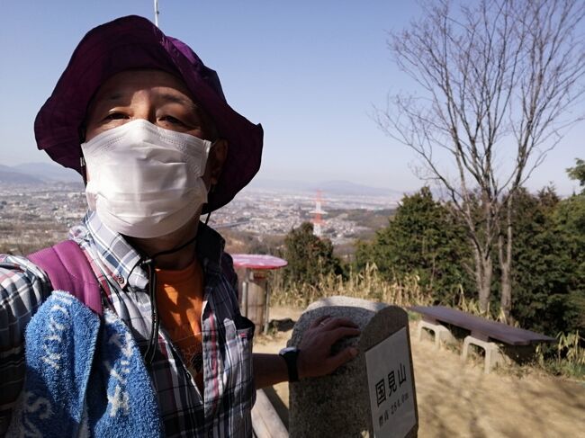 2021年3月18日(木)2時15分過ぎ、交野いきものふれあいの里の白旗池の東、交野カントリー倶楽部のグリーンに向かうカート道の下のトンネルを抜けると枚方市に入り(下の写真1)、北側にコースを変える。<br /><br />白旗池から5分余りで枚方市野外活動センター方面との分岐。分岐を右に辿ると、「にほんの里100選」に選ばれた枚方市南東部・穂谷の大自然の中にある野外活動施設に至る。<br /><br />1970年にオープンし、1992年にリニューアルされた施設で、183,400㎡の広さにメイン・ホール、3種類の広場、天体観測棟、グリーンスポーツ場、フィールドアスレチックなどがあり、宿泊は5棟あるロッジ、20張りのフレッシュエアー型テントで可能。その他、野外炊事場、水洗トイレ、最大450人使えるキャンプファイヤー場もある。子供からシニアまで市民以外誰でも使用可能で、四季を通して自然体験やアウトドア活動をすることができる。また、府下最大級の天体望遠鏡で天体観望もできる。<br /><br />ここからは国見山自然巡回緑道を北に向けて歩く。緩い上り坂が続く。この道は津田サイエンスヒルズから国見山方面へのハイキング道として整備されたもので、以前は豪雨により、階段や歩道が崩れ大変危険な状態になっていたが、2015年に大規模な改修工事が実施され、安全に通行できるようになっている。<br /><br />野外活動センターとの分岐から7分くらい、緩やかな登りを進むと右手に尊延寺地区方面との分岐。ここから緩やかな下りになる。尊延寺地区方面への道は通行止めだった(下の写真2)。さらに5分ほどで、今度は左手に清水谷方面への分岐(下の写真3)。この道でJR津田駅に出ることも出来るようだ。その分岐のすぐ先、左手に国見山山頂へ木の階段。100mで山頂とのことで頑張って登る。<br /><br />2時半、白旗池のいきものふれあいセンターから約1㎞、25分ほどで無事国見山山頂に到着。一気に下界の眺めが広がる。国見山は標高284m。生駒山地の北端に近い西側にあり、枚方市の南中央部、交野市が食い込んでいる部分で交野市倉治地区と接する部分、古くは津田村だった辺りを見下ろす。<br /><br />ここは津田城跡で、楠氏の末流楠正信が戦国時代の1490年に城を築き、津田周防守正信と称したと伝えられる。以後4代約100年間この地で勢力を揮ったが、1575年、織田信長が河内平定のため藤坂・津田を洞ヶ峠から攻め、国見山城も焼き払われた。<br /><br />この時の城主、4代津田主水頭正時はその後、西麓に標高113mの本丸山城を築いたが、山崎の合戦で明智方に付き、その城も焼き払われ、秀吉に津田・尊延寺などの領地を没収された。ただし、その後は赦され、秀吉に仕えた。同じく西麓にあった国見山城以前の館があったとされる古城も含めて津田城と総称される。<br /><br />山頂からは河内、摂津、山城方面を一望でき、「枚方八景」に制定されている。北側には宇治川・木津川・桂川の合流地点を隔てて京都の市街が広がり、その向こうに比良・比叡のひときわ高い山容を望むことができる。その左手には、石清水八幡宮のある男山と天王山の狭間から淀川が南流して、摂津と河内を二分する。さらに南に淀川が大阪平野から大阪湾まで続き、淀川の先には六甲山もあるが、この日はそこまでは見通せなかった。<br />https://www.facebook.com/media/set/?set=a.6437637709639532&amp;type=1&amp;l=223fe1adec<br /><br /><br />交野いきものふれあいの里へ引き返し、交野山山頂へ向かうが、続く