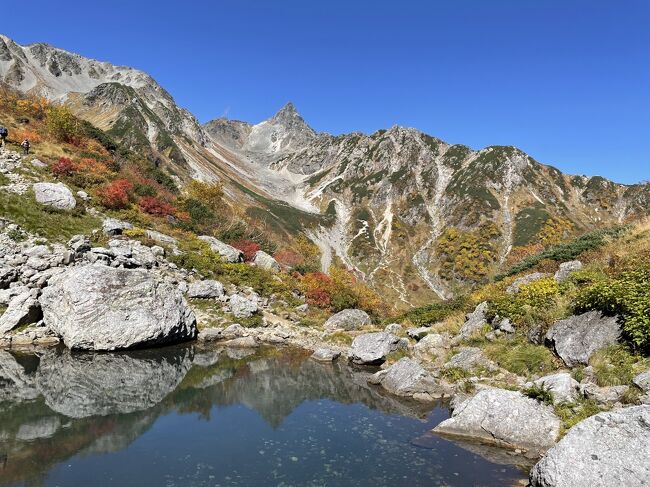 今年最初で最後のつもりで臨んだ9月の縦走が、飛騨地方を襲った地震によりあえなく撤退を余儀なくされたのが二週間前。<br />ザックまで新調したのにこの有様かと意気消沈しましたが、臥薪嘗胆、不撓不屈、あらゆる四字熟語に励まされ次の機会を虎視眈々とうかがう日々。<br />その甲斐あってかどうやら10月第一週が天気上々らしい！<br /><br />日程は最大三泊四日で候補は四つ。<br />①蓮華温泉～蓮華岳の後立山連峰縦走<br />②弥平四郎～大石ダムの飯豊連峰縦走<br />③菅の台～越百山～木曽駒ヶ岳の中央アルプス縦走<br />④槍ヶ岳～立山の前回リベンジコース<br /><br />②③は毎年機会を狙っているとても気になるルートですが、どちらも二泊三日で十分。三泊使うのはもったいない気がするので今回は却下。<br />残る①と④を比較して、未踏区間が多い①が第一候補となりました。<br />気がかりなのは①には日本三大キレットのうち不帰と八峰の二つを含んでいること。高所恐怖症のわたしには大問題です。<br />予習のためにYouTubeで不帰キレットと八峰キレットの動画をさんざん視聴した結果出た結論は<br />・体力面…問題なし（なんなら二泊三日でも可）<br />・技術面…へたっぴだけど体力で十分カバー可能<br />・恐怖心…出たとこ勝負、その場にならないとわかりません…<br /><br />出発前日には、楽しさより怖さが勝るルートを達成感のためだけに歩くのは本末転倒な気がして中房温泉行のあるぺん号を検索するもタッチの差で満席に。仕方ない、計画通りに行ってやるか！<br /><br />そして迎えた出発当日の朝。出勤前に何気なく上高地行きのバスを検索すると残席１の表示が…<br />これは神の啓示か？なにも表銀座だけが槍へのルートじゃあるまいし。未踏の槍沢ルートを歩くのも悪くないんじゃないか。天狗池からの逆さ槍も見てみたいし。<br />というわけでその場で方針変更。仕事終えてから慌ただしく装備替えをして、無事車中の人となりました。