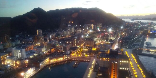 写真は門司港タワーから見た門司の街と山々の風景です。<br />全体的に私の思い出が淡い半透明のベールで覆われています。<br />(写真の技術がただ低いだけだと思いますが)<br />街は明るいイルミネーションに照らされ知らない顔つきを<br />していましたが、<br />山々の形は昔と同じで懐かしさを感じました。<br /><br />山ねむる山のふもとに海ねむるかなしき春の国を旅ゆく 牧水<br /><br />私の想い出もあの山の麓に眠っているようです。<br /><br />このブログは「旅の道草」として私の故里の思い出が主体と<br />なります。<br />今回の旅にあまり関係のない内容ですので<br />お時間のない方はスキップしていただければと思います。<br /><br />今回の旅のもう一つ目的は私が生れた故郷門司を訪ねることでした。<br />今も私の記憶の奥底に残っている故郷の原景は今はどうなっている<br />のだろう。<br />訪れるのが怖いような、そしてときめく様な不思議な想いが<br />胸の中に浮かんで来ました。<br /><br />私が37歳の時に故郷について書いた文書が残っていましたので<br />引用いたします(少し長いのですが…)<br /><br />“ふるさと随想”<br />私が37歳の時に書いた文書(1988年12月10日)<br /><br />『風の中を歩く』<br />「夢の総量は空気であった…」<br />の冒頭で始まるのは坂口安吾の「ふるさとに寄する賛歌」であった<br />と思う。<br />私の故郷である北九州市の門司区(当時は門司市と呼ばれていた)の<br />思い出も淡い半透明のベールで覆われて今でも懐かしさを感じさせる。<br />昭和35年の秋までの短い11年であったが、<br />私の幼年期と少年前期の重要な時間の中でも私のメンタリティの基盤を<br />形成したようである。<br />私の記憶に残る“ふるさと”の風景は空と雲と風の音と暖かい陽だまり、<br />草の香り、そして家の裏山に続く風師山のモナドック(残丘)の頂きに<br />続いている山笹のスロープである。<br />眼下の関門海峡には長い航路で赤錆の浮いた大小の貨物船が行き交う。<br />大河のように潮の流れが青い渦を作る海峡の中央に取り残された砂州<br />のような船島<br />(通称“巌流島”と呼ばれていた)が白い波に洗われている。<br />夕暮れになれば島の灯台の灯が点滅を始める。<br />小学校に上がる前の頃は、縁側に座って、海峡の船を眺め、<br />対岸に並ぶ下関の街を見つめ、そのまた向こうに続く白い空を<br />飽きることなく眺めていたものである。<br />太陽は裏山の後ろから登るので朝の明るさは遅く始まる。<br />夕陽は目前の下関の山々の裏に沈みきるまで、残照が赤く山の端を<br />染め、ゆらゆらと赤金色の帯が海峡を渡り、山の斜面を駆け登り、<br />私の座っている座敷の奥の襖を黄金の光で輝かせ、柱の陰影を深くし、<br />そしてたちまち赤紫色に転ずる時間の流れを楽しんでいた。<br />幼い心にも港の街から吹き上げて来る夕風の中に、街の音を聞き、<br />人の声を聞き分けることが出来る時刻は、妙に甘くもの悲しい感触が<br />心の中に広がったことを思い出す。<br />今でも夢の中にふるさとの風景と一緒にこの感触が浮かび上がる<br />時がある。<br /><br />裏山の後ろはソ連で下関の山の向こうはアメリカだと兄に言われ、<br />いつかあの山々を越えて行きたいというあこがれに胸がときめいた<br />ものだ。<br />題名は忘れたが、今でも時々口ずさむ歌がある。<br />遠い山の向こうの知らない街よ<br />いつか馬車に乗って行きたい街よ<br /><br />この歌を口ずさむとき、数十年の時空を超えて、小さな宇宙の<br />陽だまりの中で息づいていたあこがれの念が蘇って来る。<br />この想いが私の潜在意識に組み込まれてしまったためだろうか、<br />青年期には憑かれたように旅を続けるようになった。<br />幾山河越え去り行かばさみしさの果てなむ国ぞけふも旅行く―牧水<br /><br />二十歳のころはこの歌の通りに人生を旅で暮らしたいとあこがれた<br />時もあったが、<br />社会人となり、この思いは“人生の旅”という形に転化された<br />ようである。<br />この旅の途中で妻に巡り合い、子供は娘が三人となりにぎやかな<br />同行人が増え、<br />さびしさを感ずるひまもない道中となってしまった。<br />今日もまた心の鉦(かね)を打ちならし打ちならしつつあくがれゆく<br />ー牧水<br /><br />人生の風光を家族三人で旅を続けるのもまた楽しいものである。<br /><br />もう30数年前に私の故里の門司へ家内と娘たち3人とで<br />訪れたことがあります。<br />その時はスペースワールドで遊んだり、別府の地獄温泉を見たり、<br />子供たちと阿蘇山の火口をのぞき込んだりして楽しみました。<br />ワイワイ、ガヤガヤの家族旅行でしたので今回は一人でゆっくりと<br />私の故里を訪ねたいと思っています。<br /><br />以下で門司から博多までの旅程の中で私の故里を訪れた時の<br />顛末を報告いたします。<br />