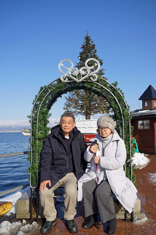 函館2日目は早朝の温泉からスタートです。啄木亭の大浴場は最上階にありますが雪が降っていると頭が凍りそうになるくらい寒いです。出発は午前9時30分ですが、実質のツアーは今日からなので早めにフロントに降りると、トラピックスのカウンターが設けられ、手続きをするように促されます。今回のツアーはバス2台で我々は東京から参加している1号車、2号車は関西からのお客さんのようです。まずは函館市内の観光で、函館朝市に向かいます。ここで1時間の自由時間になり「駅二」でイカ釣りをして刺身を食べようと考えていましたが、不漁のせいでどこのイカ釣りも休みでした。当初はお土産を買うつもりはなかったのですが、キンキがあまりに美味しそうだったので、地元の友人へのお土産も含めて5枚送ってもらうことにしました。安くしてもらった分イカの一夜干しも追加しました。夏に行った釧路の和商市場に比べると2割くらい高いような気がしたのと、カニは全く美味しそうに思えませんでした。これは札幌の二条市場も同じだったのでちょっと残念です。バスに戻る前に時間があったので青函連絡船の摩周丸の外観も見に行きました。次はベイエリアに戻って90分の自由時間になって、ここでお昼まで食べることになります。最初に入った海鮮市場のフードコートで生ガキと北寄貝の刺身を日本酒で楽しんで、お昼はラッキーピエロでチャイニーズチキンバーガーと生ビールをいただきました。お昼を食べた後は高速道路に乗って、八雲のサービスエリアの「噴火湾パノラマパーク」にちょっと立ち寄って、洞爺湖の「わかさいも本舗」に立ち寄って、この日の観光は終わりです。函館以降は天気が良かったので楽しめましたが、雪でも降って景色が見えなかったらただのトイレ休憩だなと思いました。洞爺湖を出て高速に乗ると1時間ほどで2泊目の登別温泉に到着します。<br />