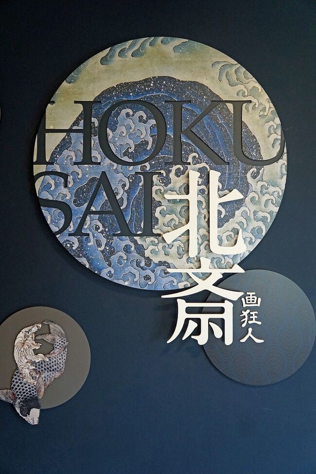 「岩松院」の参拝を終えるとドライバーさんの言う通りちょうど良い時間でした。ここからは「北斎館」の近くのバス停まで戻ります。結果的には2回しか乗りませんでしたが、「おぶせロマン号」というバスは便利でした。1日500円ですが、「岩松院」までタクシーで片道で1,200円くらいかかるということです。町中に戻って「栗の小路」に入ります。ここでその名前の意味が分かりました。栗の木の間伐材の小口出しのウッドブロックにして道路に敷いてあるのです。なるほど栗は水に強く、昔は縁側の板に使われていました。その小路の周囲もきれいに整備されていて気持ちよいです。町屋には「Welcome to My Garden」という板が掲げられ、オープンガーデンになっているので誰でも自由に見学することが出来ます。これはいくつも見ることが出来ましたし、店の中を通過できたり酒蔵の敷地を通り抜けることも出来ます。小布施の町が住民も含めて町おこしを成功した理由が分かった気がします。街中ではまず「高井鴻山記念館」の見学をします。元々邸宅だった建物が記念館になっていますが、初めて高井鴻山の作品や経歴について学びました。車では葛飾北斎を小布施に招いた人くらいの知識しかありませんでした。妻は勉強するとお腹が減るので、枡一酒造の経営する「蔵部」というおしゃれなレストランに入りました。もう午後1時になろうとしているのでお店は空いていました。テラス席が気持ち良さそうなので、そこに席を取りました。4月中旬とは言え信州の山の中でもポカポカの陽気で、25℃くらいにはなっていたと思います。ここでは地産の食材をふんだんに使った料理がいただけ、昨日の昼から今朝までのフラストレーションが全部吹き飛びました。お腹がいっぱいになった後は「北斎館」で小布施における葛飾北斎について学びました。豪華で見事な山車は見ごたえがありました。