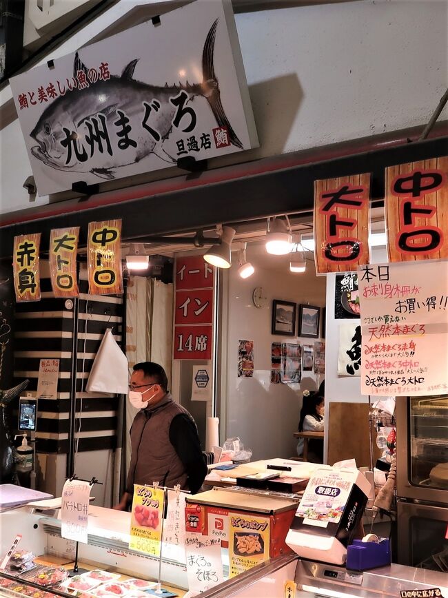 旦過市場 については・・<br />https://www.tangaichiba.jp/<br /><br />旦過市場（たんがいちば）は、福岡県北九州市小倉北区魚町にある市場。北九州の台所とも呼ばれる。<br /><br />神嶽川（かんたけがわ）の東側に位置し、小文字通りをはさんで魚町銀天街に接続している。アーケードになっており、北側入口には長らく日本初の24時間営業スーパーマーケットの丸和があったが、2019年3月1日からは運営主体の変更に伴いゆめマートになった。<br />200店舗以上が軒を連ね、鮮魚・青果・精肉・惣菜などを扱う店が多いが、郷土料理の「じんだ煮」や鯨肉を扱う店もある。北九州市を代表する市場であり、福岡県内においては福岡市の柳橋連合市場と並び称される。<br /><br />主婦をはじめとする一般消費者のみならず、料亭や料理店などの料理人も買い付けに訪れる。グルメ番組や旅番組でしばしば紹介され、観光客も多く訪れる。また、近年は旦過市場の川側とは反対側の裏手に位置する「新旦過横丁」（新旦過飲食街）と呼ばれる場所に、若者をターゲットにしたお洒落な飲食店が営業しており、週末の夜には若者の姿を見ることが出来る。<br /><br />ちなみに旦過とは修行僧の雲水が宿泊する場所で、東曲輪の町屋敷と小笠原家ゆかりの宗玄寺や開善寺などとを結ぶ橋が架けられ、城下町の南玄関の香春口に通じる。<br /><br />大正時代のはじめ、隣接する神嶽川から魚の荷揚げ場として成立し、その後、田川・中津方面からの野菜の集積地となったことで市場としての機能が形成された。昭和30年代に建てられた木造建築物が密集しており、1960年代を時代背景とした映画『初恋』（2006年公開）の撮影ロケーションが行われたこともある。また、中央の通路を挟み川側（丸和側）は建物が神嶽川の上にせり出して建っている。<br /><br />このような環境のため度々災害に見舞われている。 2009年7月の中国・九州北部豪雨、および2010年7月の豪雨では浸水の被害に見舞われた。 2022年4月19日未明には新旦過横丁付近から出火し、鎮火までに約65時間を要し少なくとも42軒に延焼が及ぶ火災が発生した。<br /><br />北九州市では神嶽川の改修にあわせて旦過市場の再整備のための土地区画整理事業を計画し、2021年2月10日に「旦過地区土地区画整理事業」として事業計画が決定した。<br />計画によると、現在の旦過市場の東側（旦過駅前）に4階建てのビルを建設し、ビルの1・2階に約60店舗を収容して神嶽川側へのせり出しを解消する。再整備にあたっては区域内の店舗を順次仮区画へ移転しながら営業を継続するローリング方式を採用し、2027年度の完成を予定している。なお、2022年の火災で大きな被害を受けた新旦過横丁は土地区画整理事業のエリアに入っていない。<br />（フリー百科事典『ウィキペディア（Wikipedia）』より引用）<br />