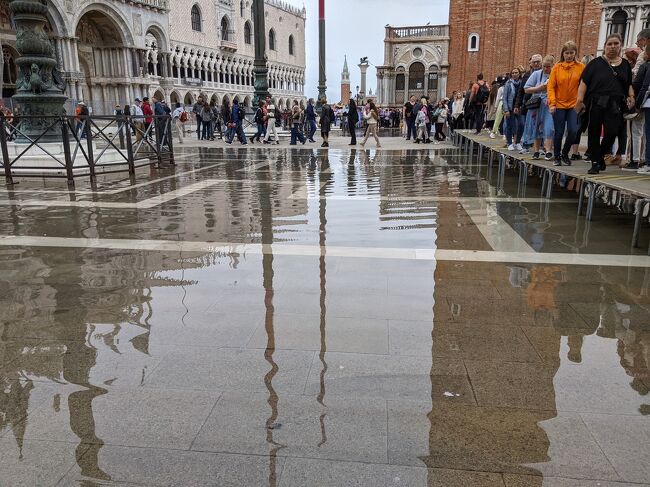 ヴェネツィア定番中の定番、サンマルコ広場<br />天気予報通りに、時々にわか雨、小雨混じりのお天気<br />広場に置いてあった踏み台？みたいなモノのホントの使い方が分かりました。<br /><br />それまでは、皆さんが腰掛ける椅子化していたので、気付かなかった、ホントの用途♪<br /><br />こんなにわか雨でも、あっという間に広場に広がる水たまり(*_*)その中をザブザブ浸かって歩かない為の、通り道に使う台座だったのね～<br /><br />これがかの有名なアクア・アルタ？<br />話によると、アクア・アルタを防ぐために、モーゼ、という水中から立ち上がる壁？みたいなのが出来たとか?<br />役立ってないじゃん？<br /><br />本来は、塩野七生さまの著作、いわゆるヴェネツィア3部作、の影響下にある私としては、もっとヴェネツィア共和政体とか、歴史、ヴェネツィアこそがインテリジェンスの重要性にいち早く目覚め、小国ゆえにその外交力でもって大国と対等（であるかのごとく）に渡り合い、生き残りを模索し、海洋国家として繁栄、イスラム圏との貿易などにより一時はその貨幣が最高の価値を持つ経済大国であったほどの栄華を極めていた、というような背景に肉薄する（せめて、ちょっと触れる）ようなブログ、書きたかったな～<br /><br />写真が多くてm(._.)m