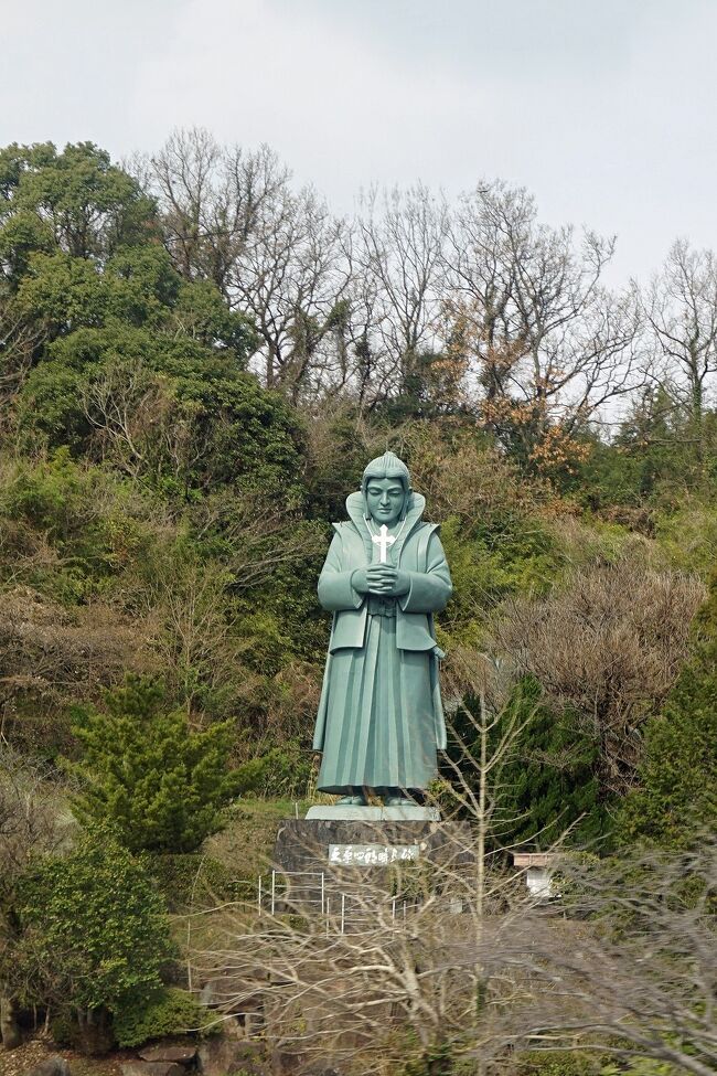 バスは宇土半島の先端の「三角西港」を離れて天草五橋の1つ目の「天文橋」を渡って「大矢野島」に入ります。しばらく走ると「藍のあまくさ村」という施設があり、そこには巨大な「天草四郎像」が立っていました。こういった情報はバスガイドさんがいなければ分からないことで、そうでなければ写真を撮ることも出来ません。ツアーの良いところはこういった情報だと思います。この像はふっくらとした上に好青年の姿で、　天草･島原の乱の悲壮感はありませんが、十字架を持って祈る姿は印象的です。バスは減速もせずに先へ進み、停車したのは「道の駅天草さんぱーる」です。ここで20分ほどのトイレ休憩になります。ほとんどの時間は農産物や海鮮の売店をひやかしていました。熊本や天草の名産品が並んでいますが、柑橘類は昨晩購入して、店から宅急便で送ってしまったので購買意欲に火が付きません。この辺りは車エビの養殖でも有名なところなので期待していましたが、シーズンオフのようでもありました。バスの車窓からでも養殖池の水を抜いて、底の砂を積み上げて消毒している光景が見られました。通りの反対側には教会の姿をした「天草四郎ミュージアム」の建物が見えましたが、立ち寄っている時間も無いので諦めました。バスは2番目の橋「大矢野橋」を通過して、「永浦島」もあっという間に通過して3つ目の「中の橋」渡ります。この辺りの橋を通過する際には小さな島や入り組んだ入り江が見え、さらにその先には島原半島が見えます。天気も良く美しい景色が堪能できました。4番目の「前島橋」も間の「大池島」も「池島」もあっという間に通過します。「前島」と5番目の「松島橋」を超えると残りは大きな「上島」と「下島」だけになります。この後の観光はこの2つの島を巡ります。島原半島の口之津を結ぶフェリーの港である「鬼池港」にも天草四郎の図が海に向かって立っています。以前はもっとたくさんの航路があったようですが、利用客の減少もあって現在は2ルートくらいしか残っていないようです。中世に南蛮貿易の通詞（通訳）が住んでいたといわれる「通詞島」の手前のレストランでらんちになりました。大きなガラス窓からは美しい海の広がりが見えます。ここでいただくのはウニやアワビの乗った海鮮丼です。これは豪華で千秋に食べた北海道の海鮮とはまた違ったおいしさがあります。追加で鵜にも頼んでしまい、ビールから日本酒とお酒も進みます。この店は熊本県のクーポンが使えたので追加料金は発生しませんでした。「通詞島」の周辺はイルカが見られることで有名なのですが、この時はその姿を見ることは出来ず、代わりに見えたのは「おっぱい岩」だけでした。バスは一度海岸線を離れますが、この辺りはレタスの生産が盛んだとガイドさんが教えてくれます。長崎県の佐世保で戦後の進駐軍のアメリカ兵相手にバーガー屋さんが出来ましたが、その当時はレタスが無くてここで栽培されたものが送られたという歴史があるそうです。その先には九州電力の巨大な苓北発電所が見えます。ここは火力発電所で、付属する港には中国から輸入された石炭が山のように積まれてありました。先ほど訪ねた「三角西港」が栄えたころには三池炭鉱の石炭を送り、現在はその逆になっているというわけです。バスは国道389号線を離れ、下島の西海岸の「十三仏公園」で停車します。ここで20分ほどの休憩になり、美しい断崖と青い海を見ることが出来ました。対岸には長崎市から南西に伸びる長崎半島がきれいに見えました。半島の陰になった裏側には「軍艦島」があるとガイドさんが教えてくれます。バスは白い「大江天主堂」を右手に見ながら「崎津」の港に入っていきます。