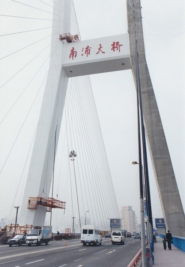 上海市街地を浦西地区と浦東新区に分けて流れる黄浦江。<br />その黄浦江にはいくつも大きな橋が架かっています。<br />上海市街地を流れる部分だけでも三つあり、上流から盧浦大橋、南浦大橋、楊浦大橋と続き、どれも目を見張る大きさ。<br /><br />そのうちの南浦大橋は、外灘（バンド）からだと中山南路に沿って黄浦江を数キロ遡った所に架かる巨大な斜張橋（中国語だと斜拉橋）。<br />1991年12月に開通したその橋は全長846ｍあるんだそう。<br /><br />今はどうか分かりませんが、2000年12月には南浦大橋の両端の支柱にはエレベーターが設置されてあり、誰でも５元で南浦大橋に上れました。<br />そこで、話のタネに行ってみたSUR SHANGHAI。<br />そこから見た浦西地区や浦東地区などの市街地風景と南浦大橋について、記録を残しておこうと思います。<br /><br />●注：　浦西地区は昔から栄えている地区で、外灘（バンド）や豫園、新天地、虹橋空港がある側。<br />浦東新区はその名の通り1990年代になってから新しく開発された地区で、よく話題に上る陸家嘴の超高層ビル群や浦東空港がある側。<br /><br />●注：　2000年の陸家嘴には上海中心大厦（上海タワー）や上海環球金融中心（上海ヒルズ、上海ワールド・フィナンシャル・センター）はまだ無く、金茂大厦（ジンマオタワー）が一番新しい高層ビルでした。<br />次のウィキペディアの≪超高層ビルの一覧≫のページで見てみるといいですよ。<br />https://ja.wikipedia.org/wiki/%E8%B6%85%E9%AB%98%E5%B1%A4%E3%83%93%E3%83%AB%E3%81%AE%E4%B8%80%E8%A6%A7<br /><br />表紙の画像は、南浦大橋の歩道から見上げた主塔部分。